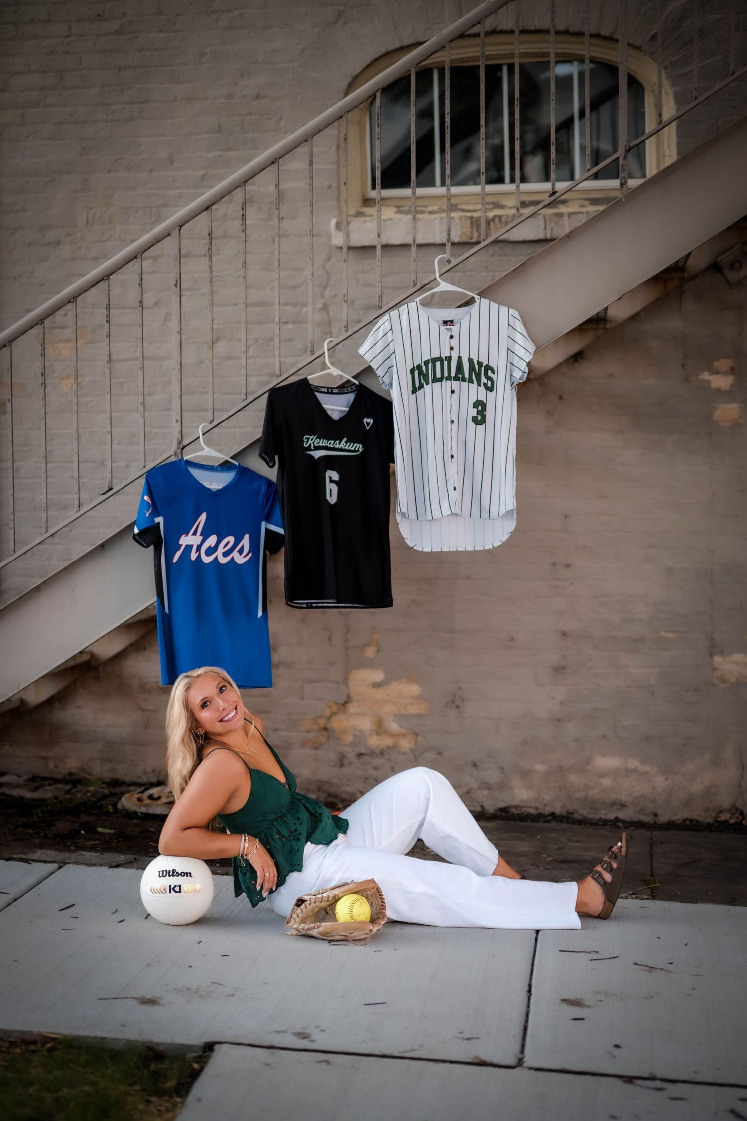 Millie with her softball and volleyball jerseys, glove, and ball for senior sport photos in Port Washington, Wisconsin