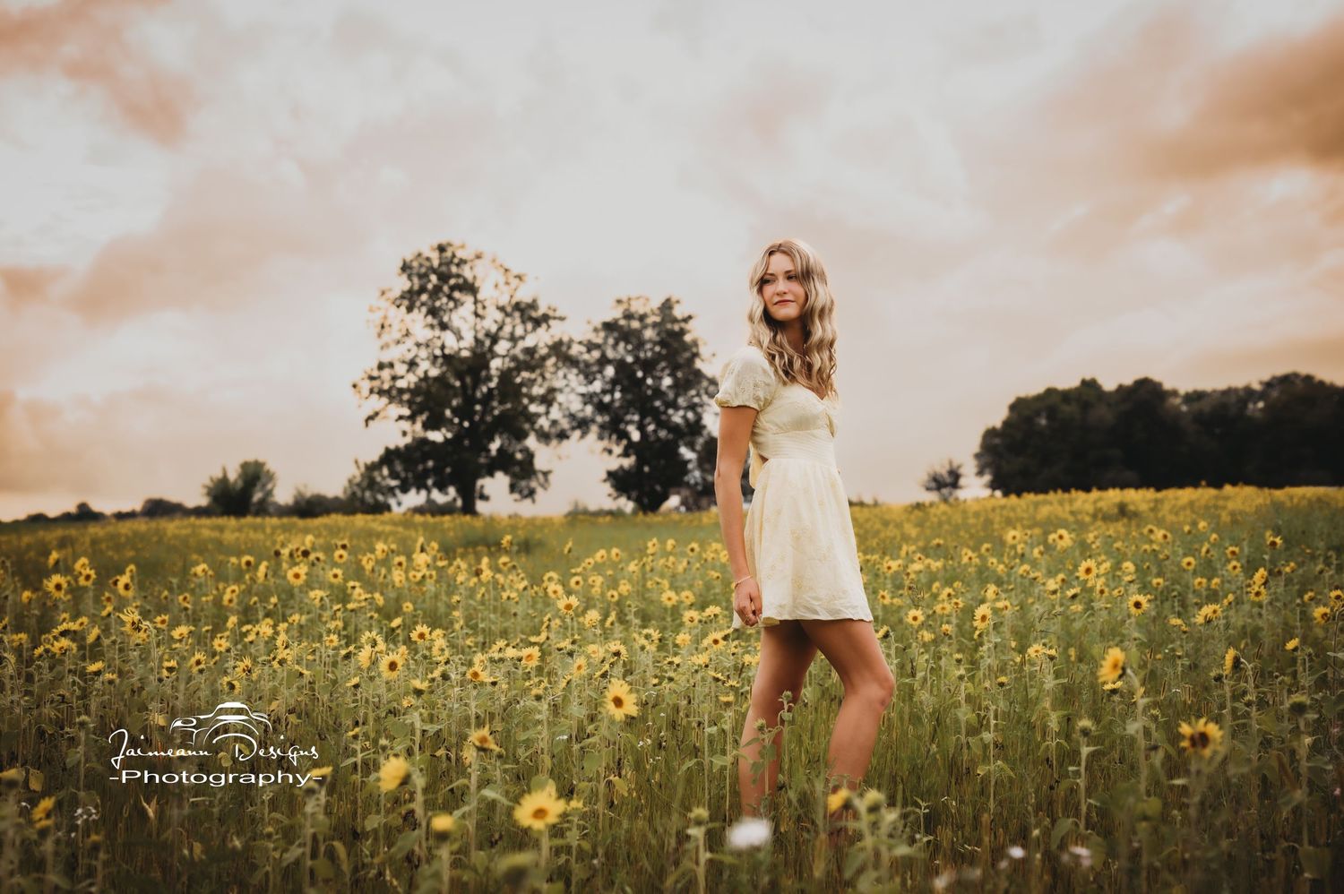 Portrait in field of yellow wildflowers at sunset with soft natural lighting.