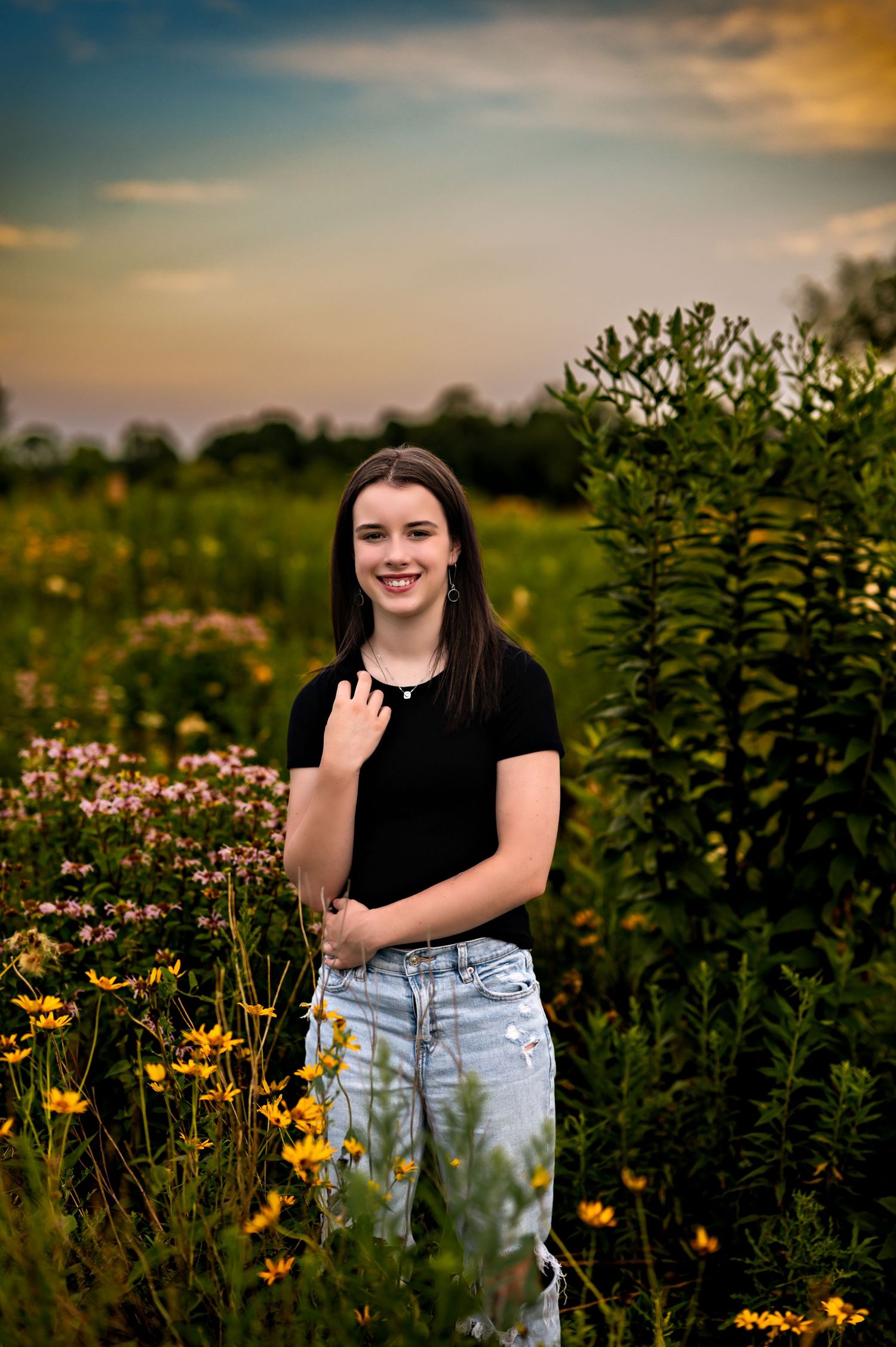 A portrait in a wildflower field at sunset with yellow blooms and greenery creating a dreamy natural backdrop.