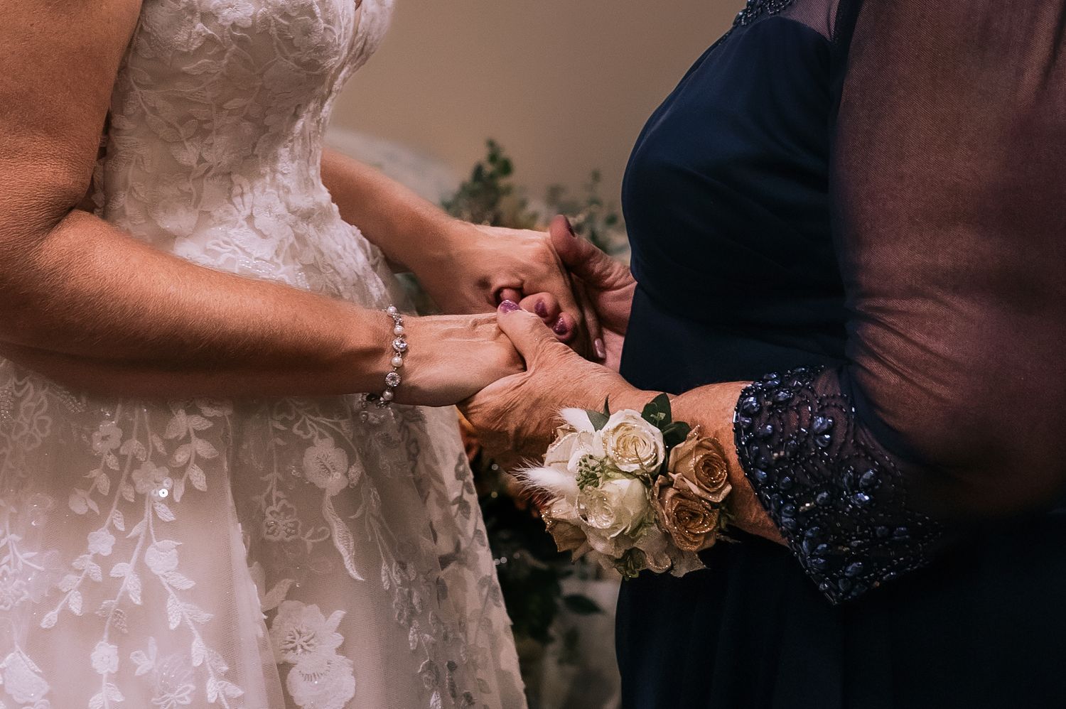 Close-up of hands exchanging a white rose bouquet during an outdoor wedding ceremony.