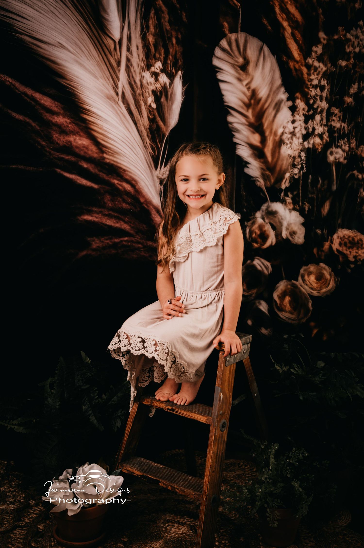 Sweet portrait on wooden ladder with boho dried floral backdrop.