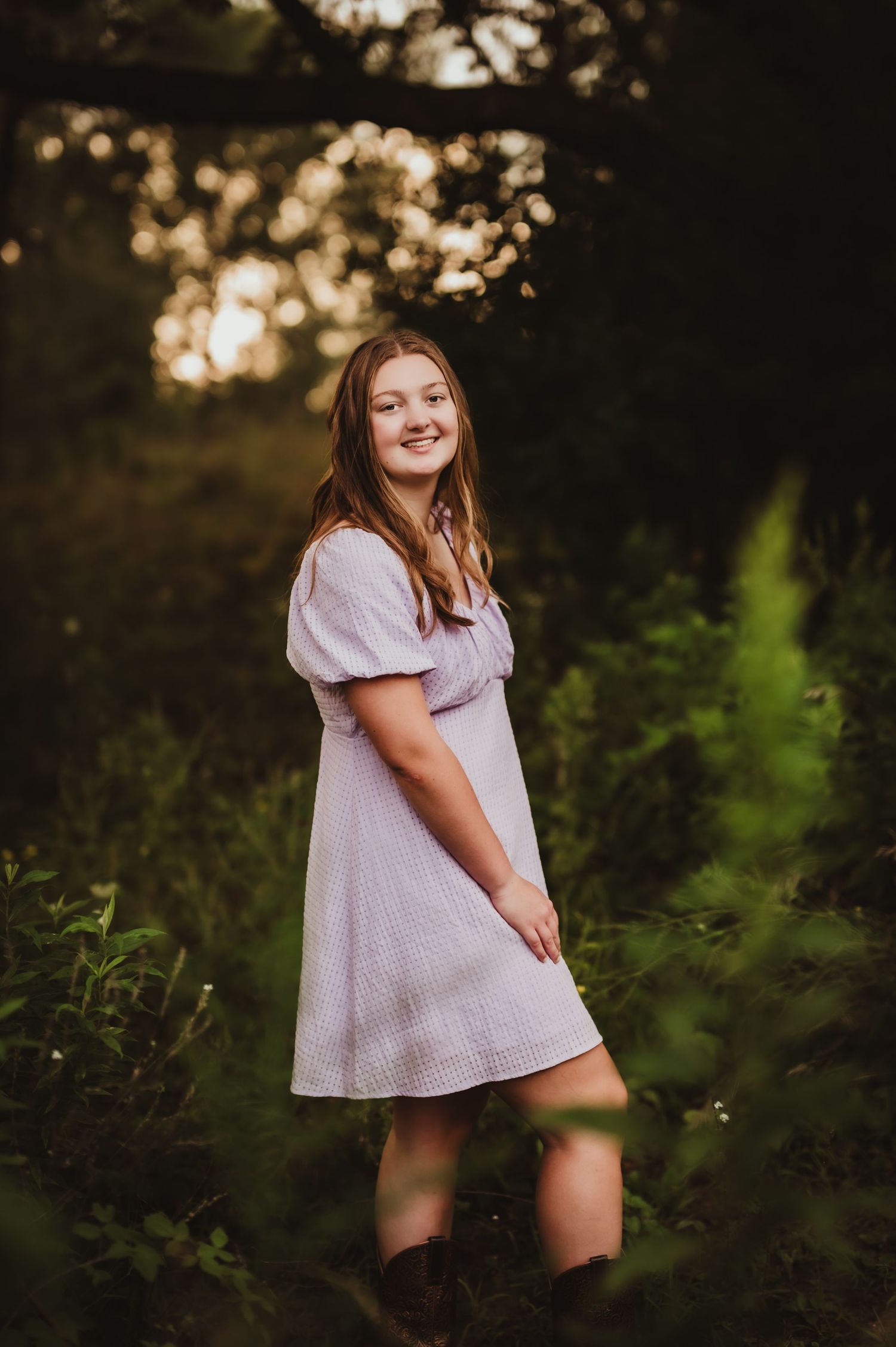 A white summer dress creates an ethereal look against a natural forest backdrop at sunset.