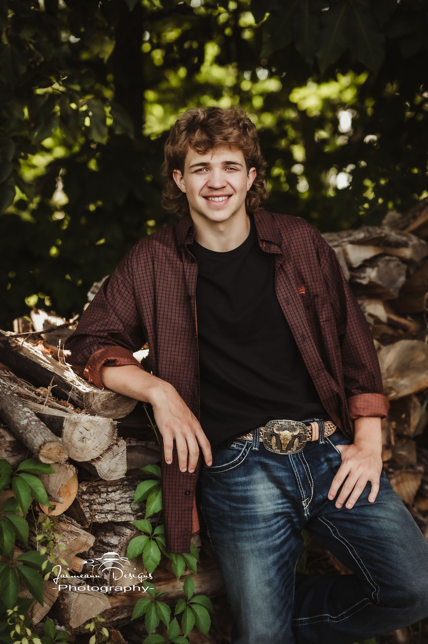 Casual portrait by woodpile wearing plaid shirt and jeans.