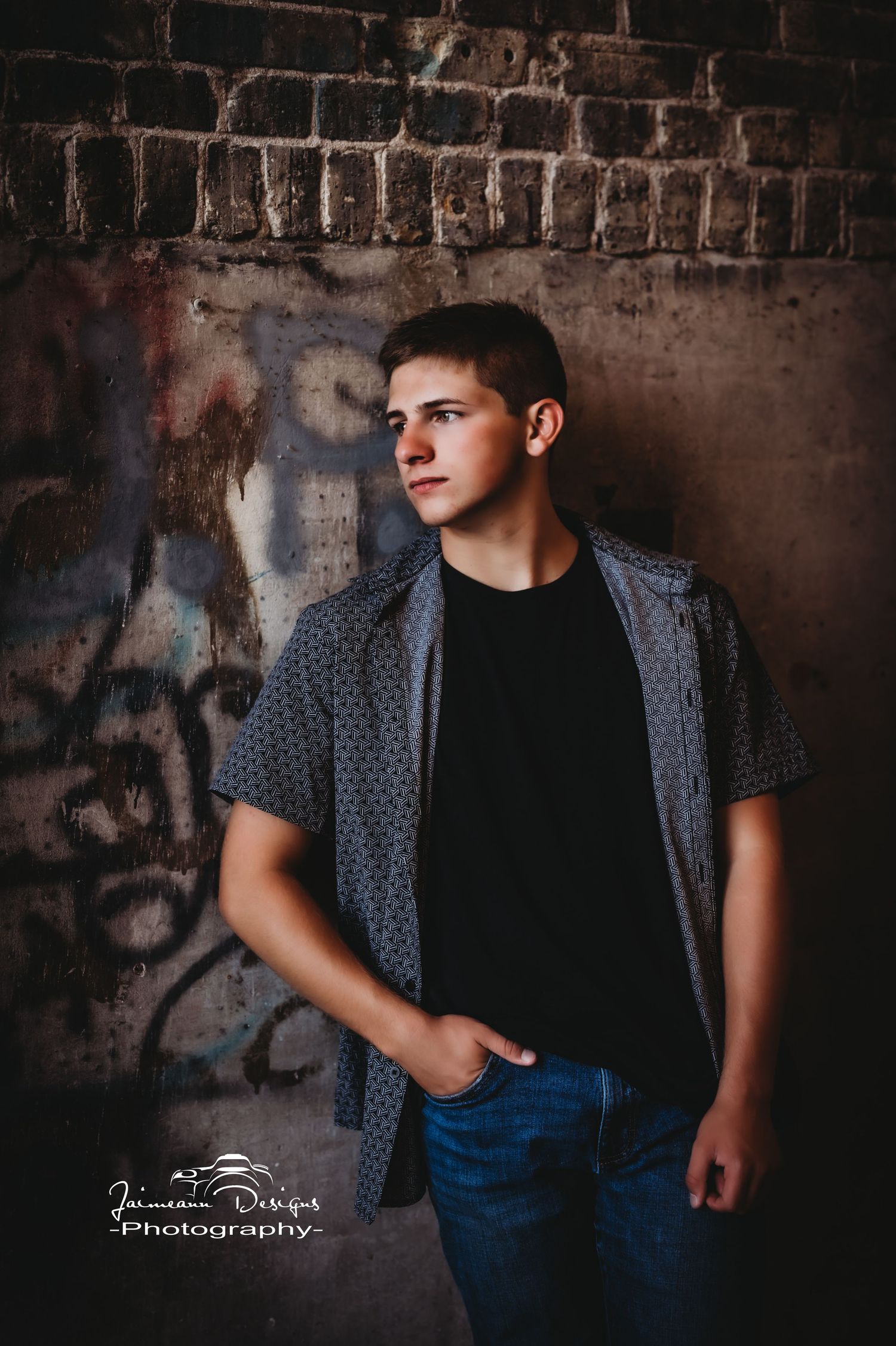 Urban portrait against textured brick wall with graffiti.