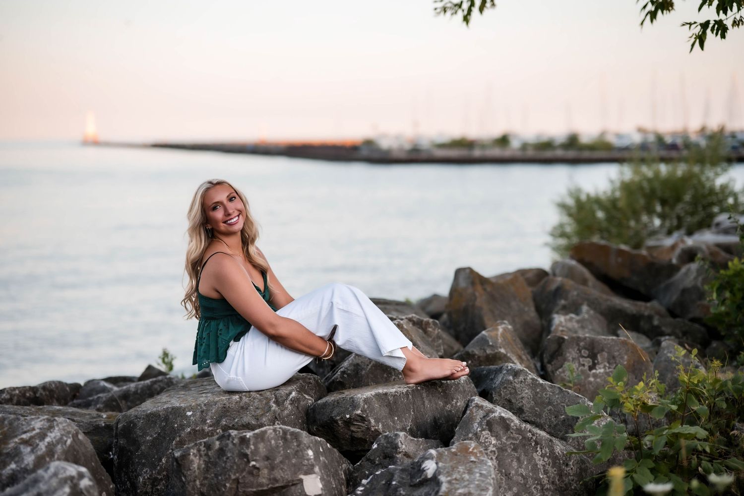 Senior girl sitting on the rocks along the Lake Michigan shoreline in Port Washington