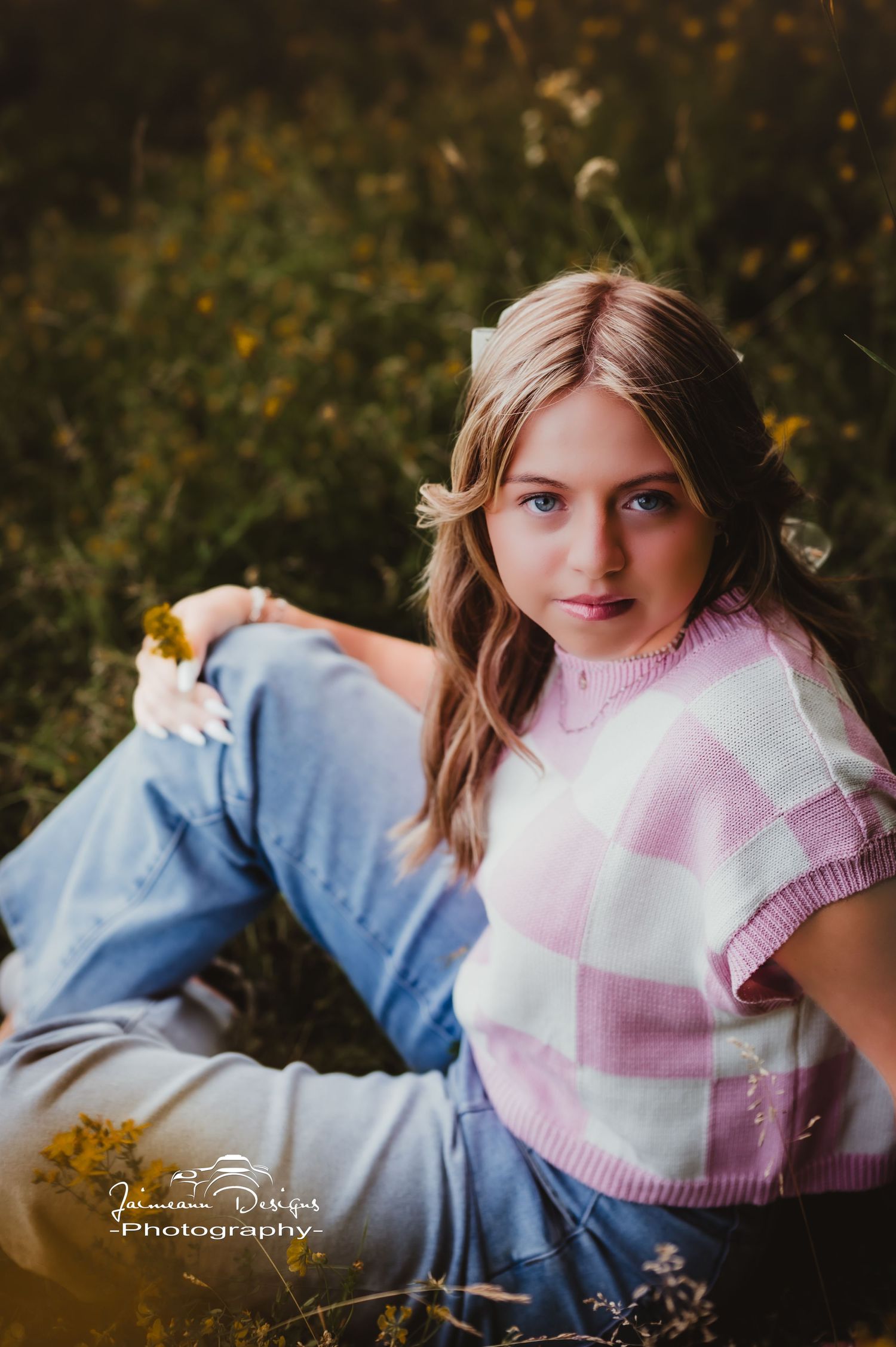 Casual outdoor portrait wearing pink checkered sweater vest and jeans.