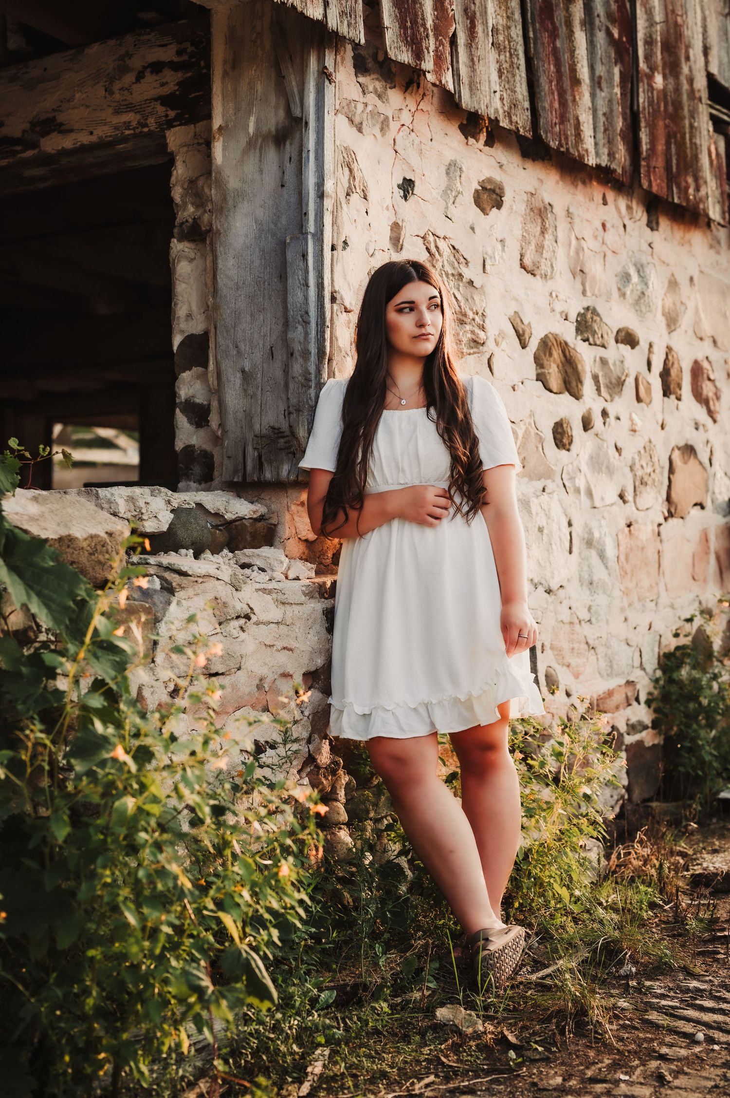 Vintage-style portrait against weathered stone building with wildflowers.
