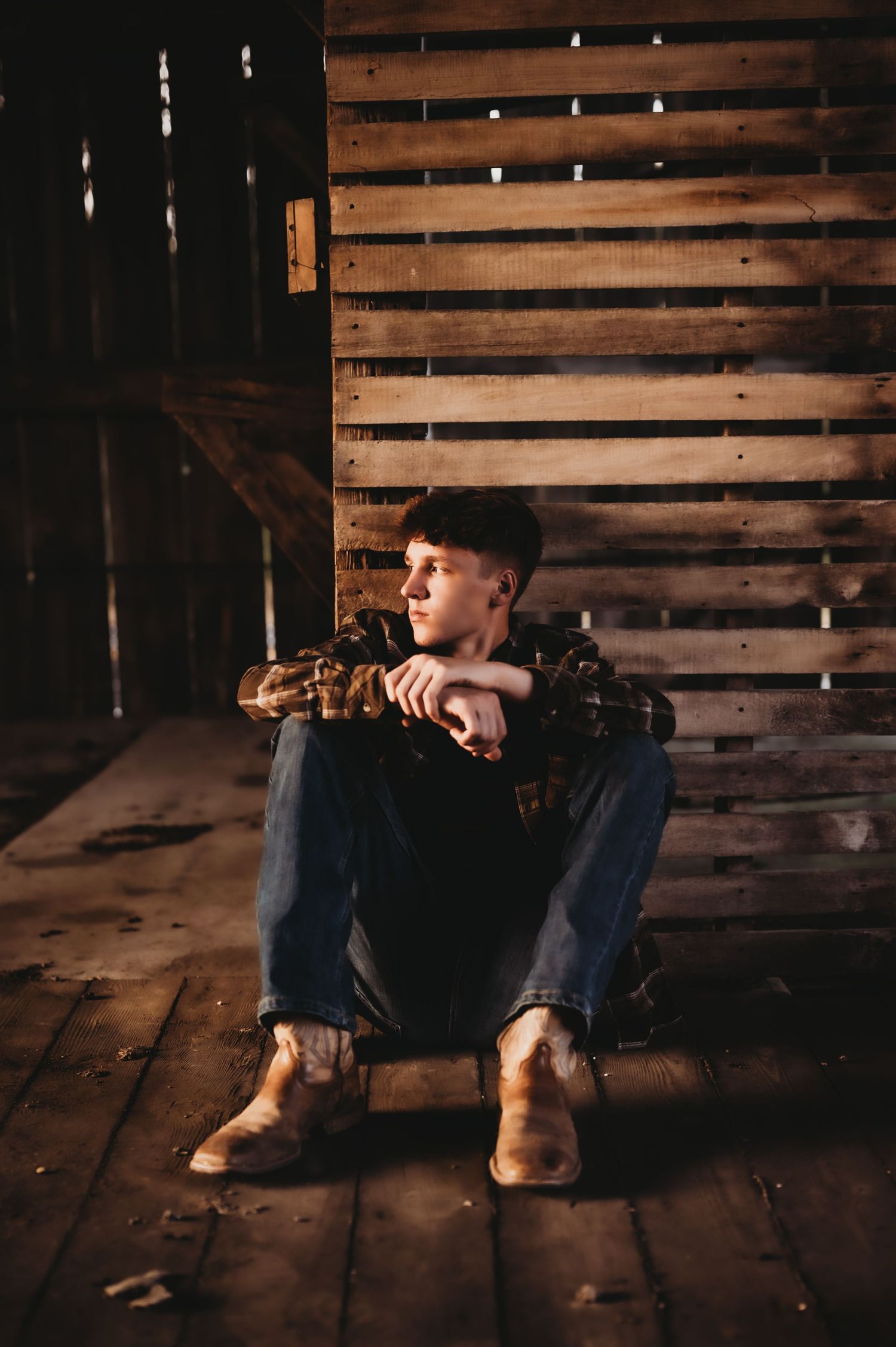 Moody portrait in rustic barn with wooden slat walls and boots.