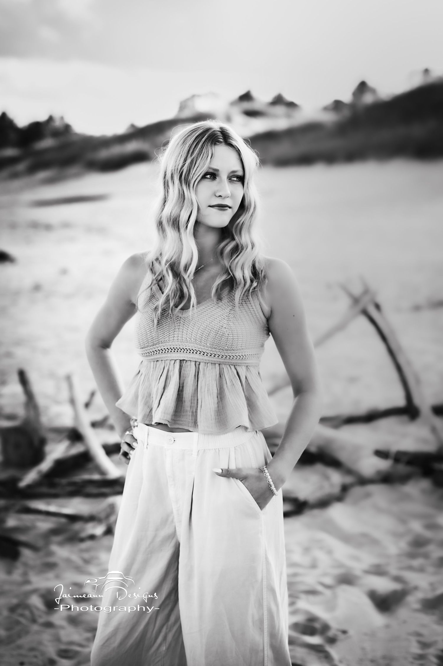 Black and white beach portrait with casual summer outfit and waves.