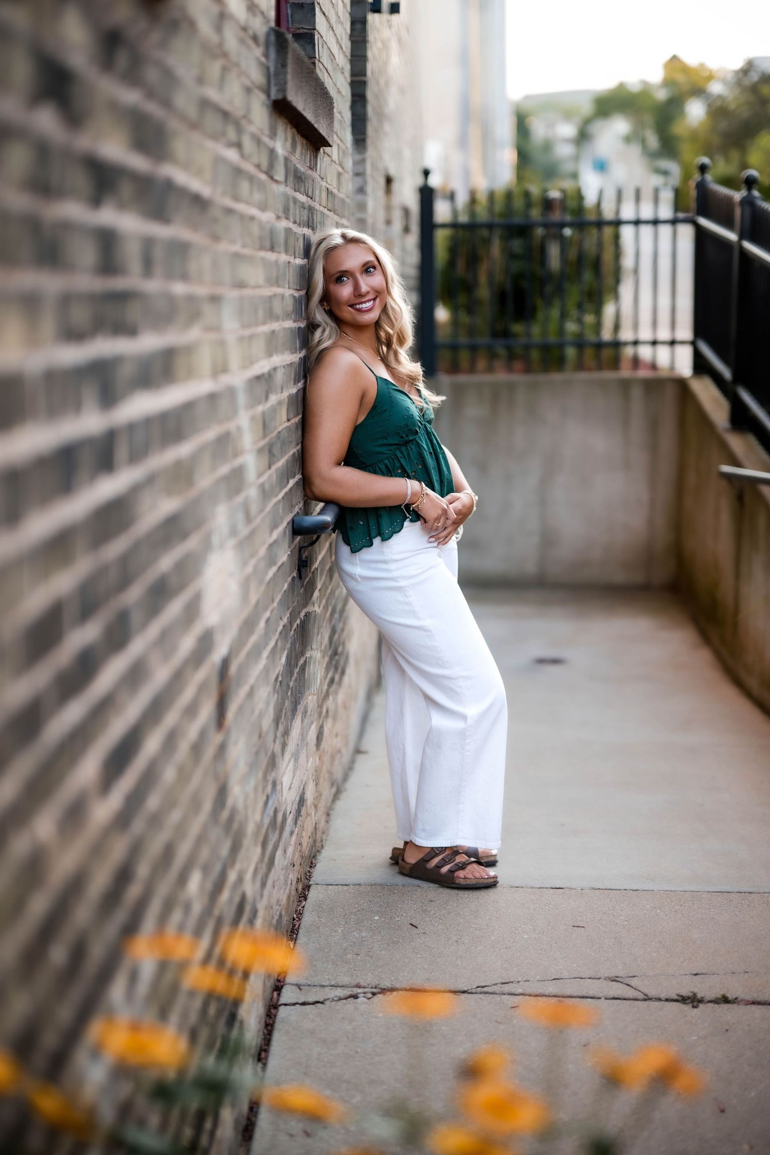Senior girl leaning against a brick wall in downtown Port Washington