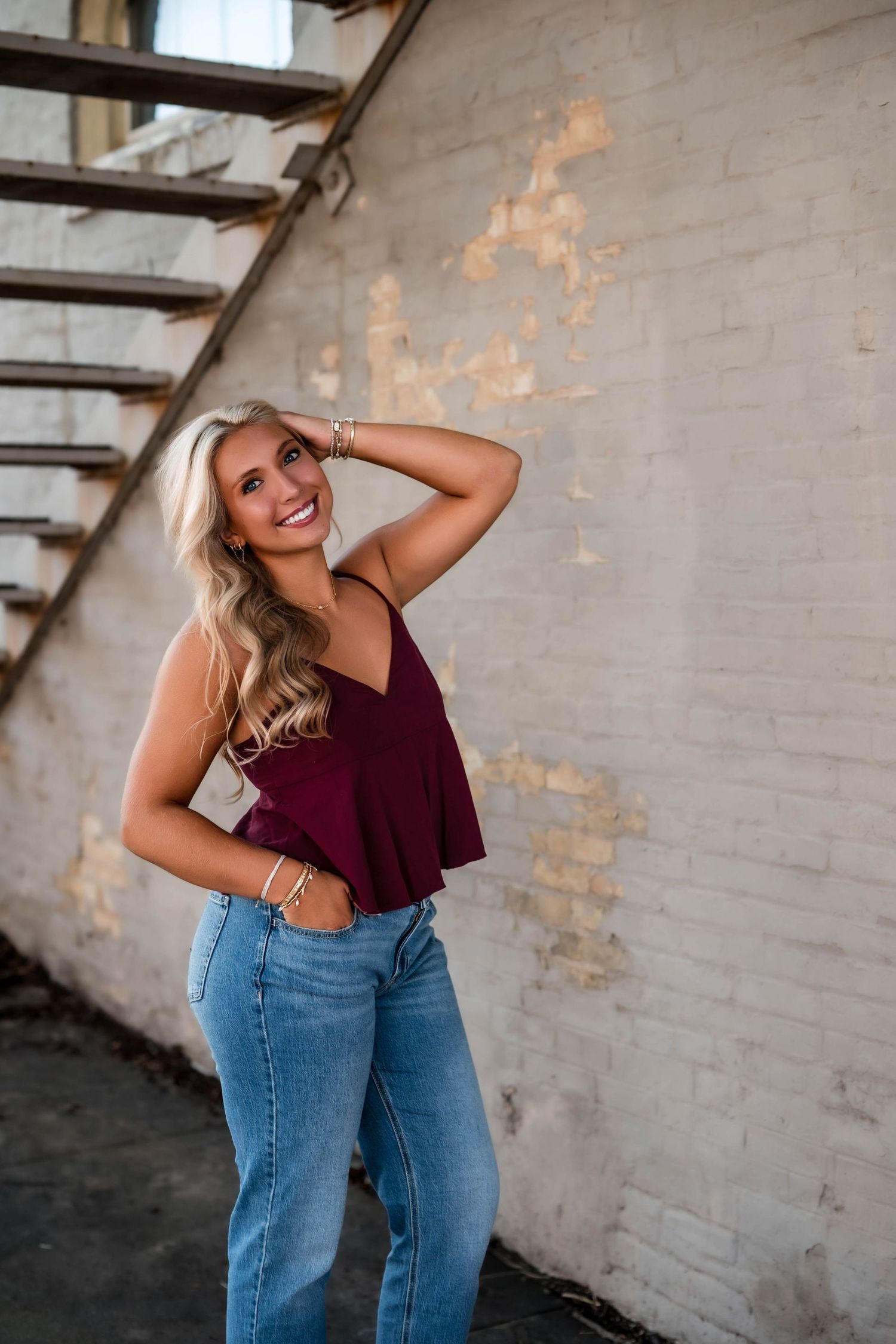 Senior girl in a burgundy top with her hand in her hair in downtown Port Washington