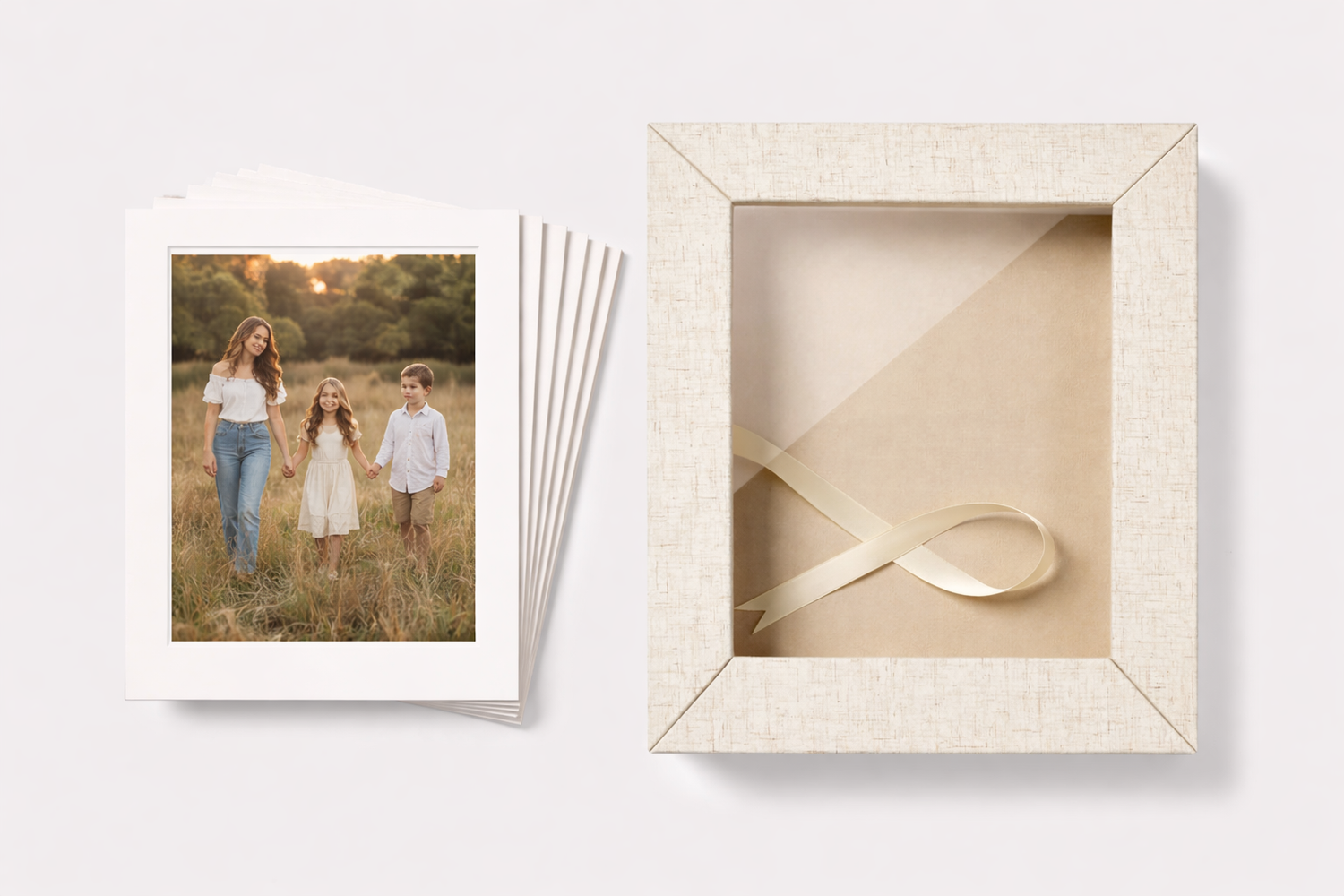 Stack of family portrait prints beside an elegant cream textured keepsake box with satin ribbon.