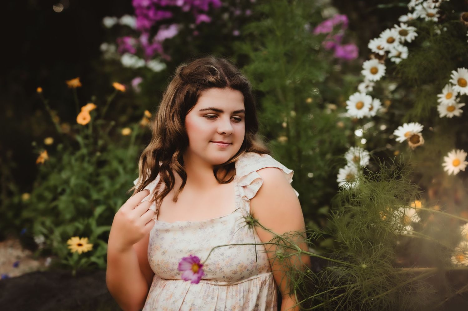 Portrait in a garden with colorful pink and white flowers blooming in the background.
