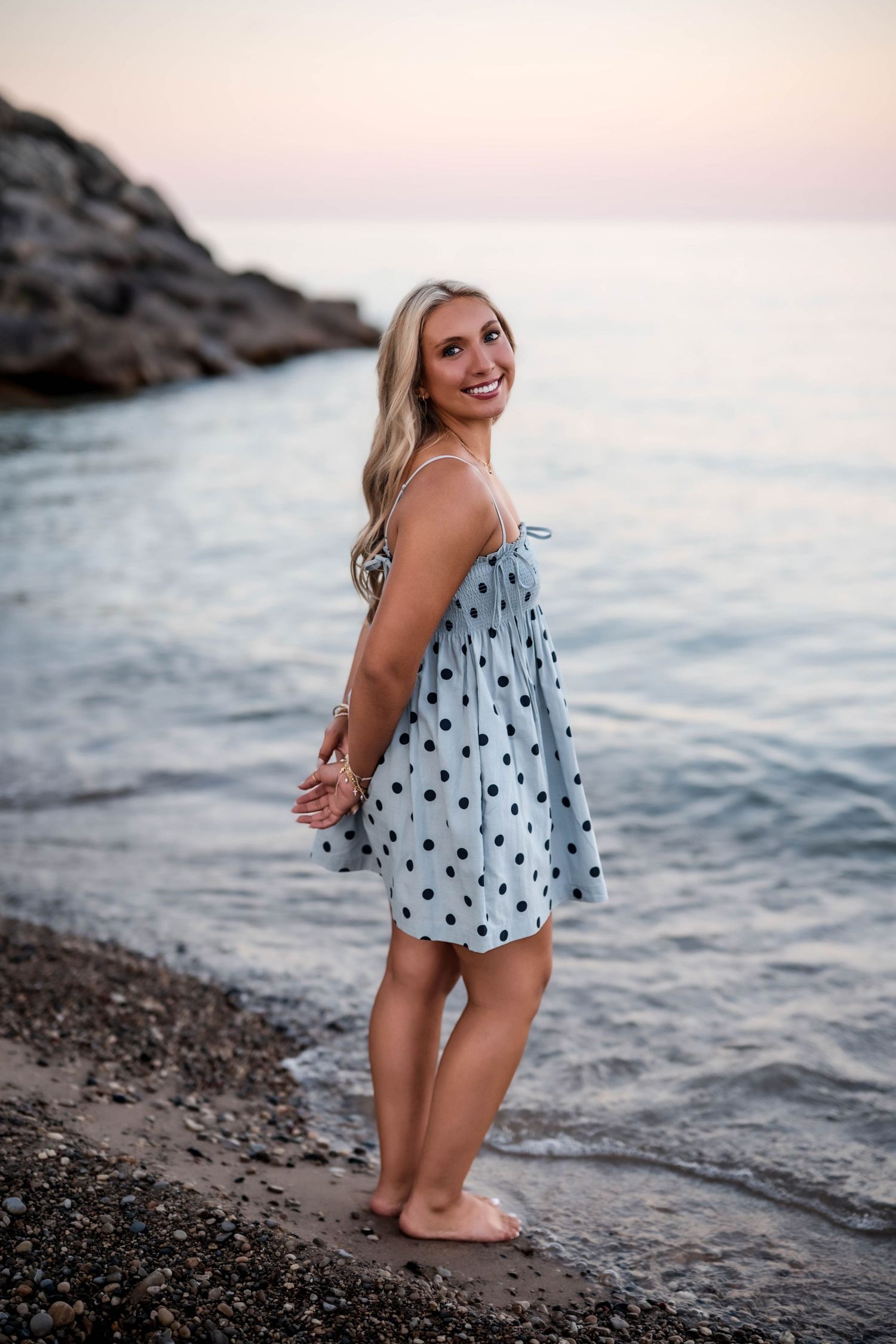 Senior girl standing in Lake Michigan in a blue maxi dress at sunset
