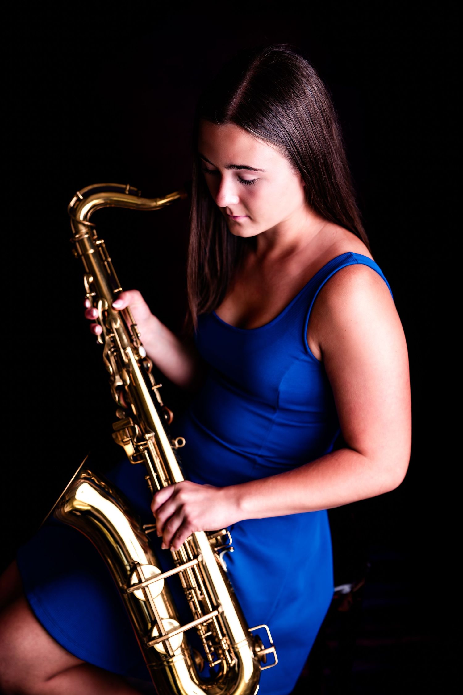A series of dramatic photos showing a saxophone player in a blue sleeveless top against a dark background in Kewaskum, WI Studio