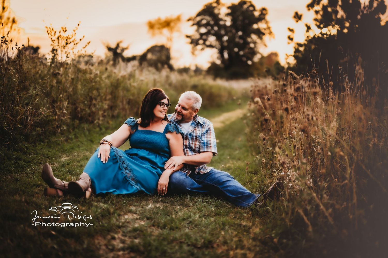 Couple relaxing together in golden wildflower field during sunset photoshoot.