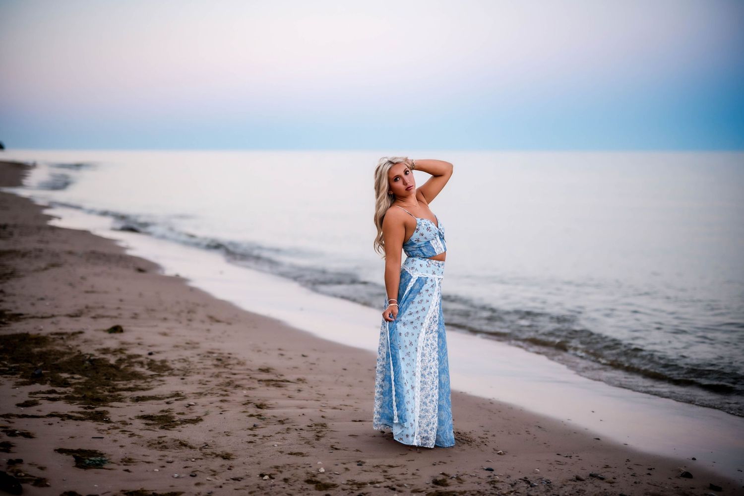 Senior girl standing in Lake Michigan in a blue maxi dress at sunset