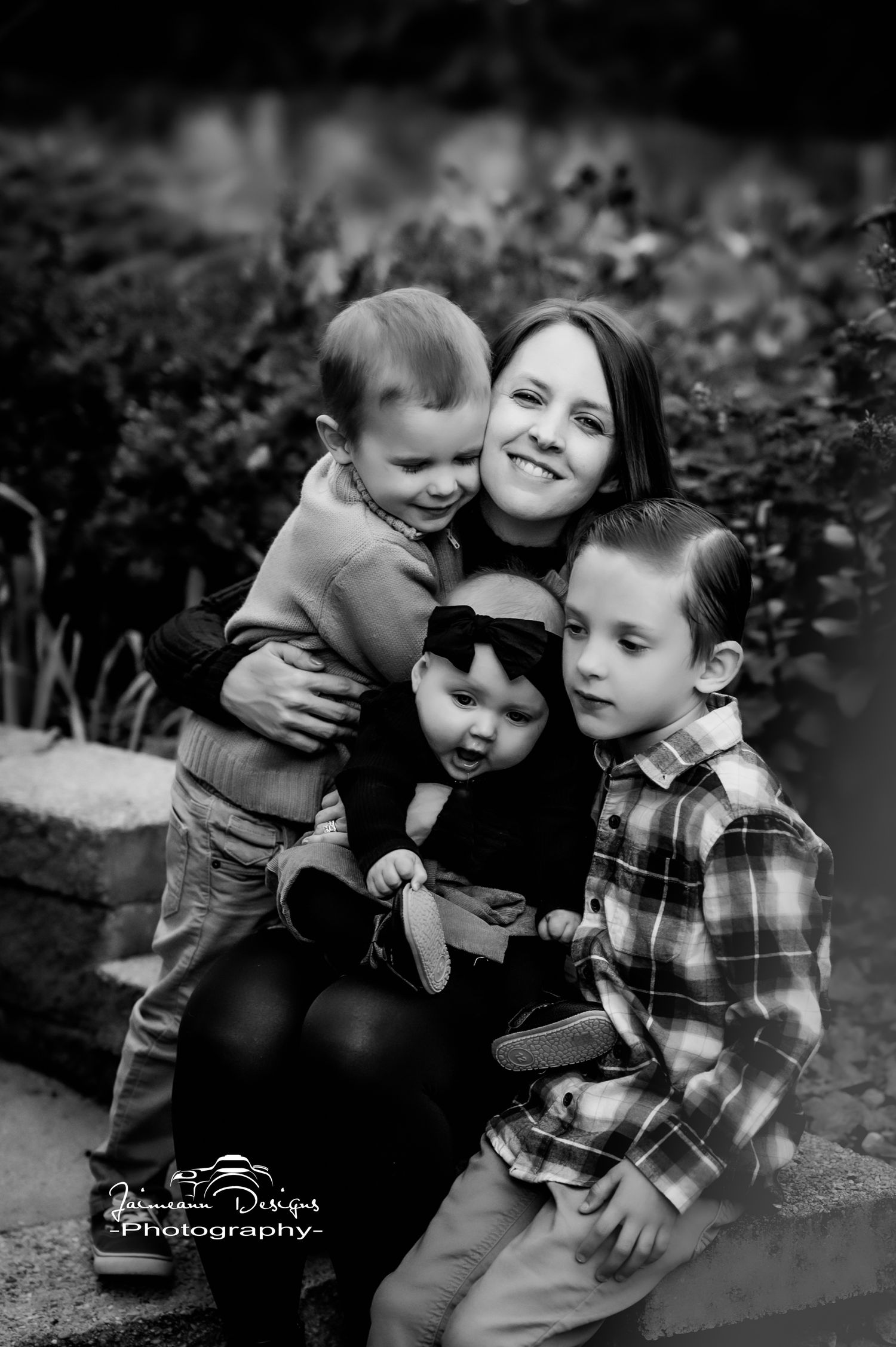 A black and white portrait of a family group sitting close together outdoors.