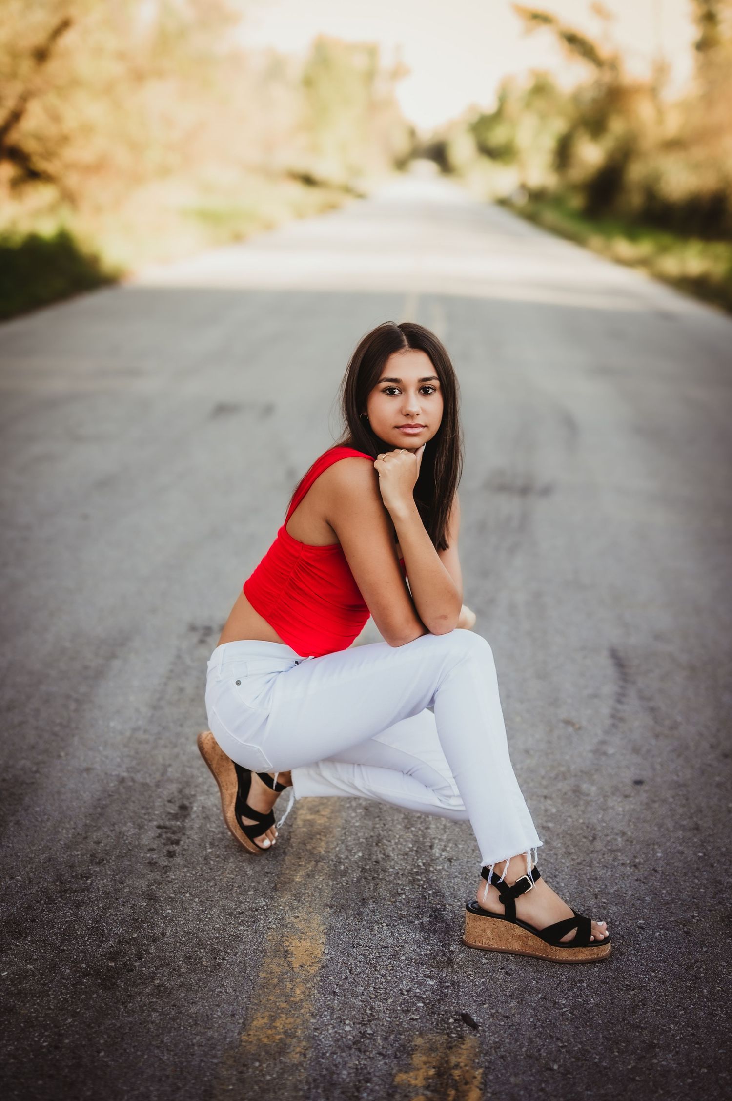 Outdoor fashion photography on an empty road with autumn trees in soft focus.
