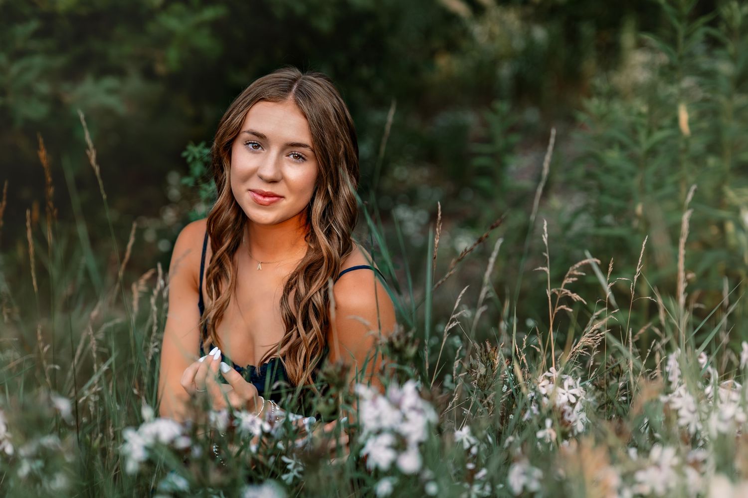A person poses among wildflowers and tall grass in a natural outdoor setting during golden hour in Slinger, WI