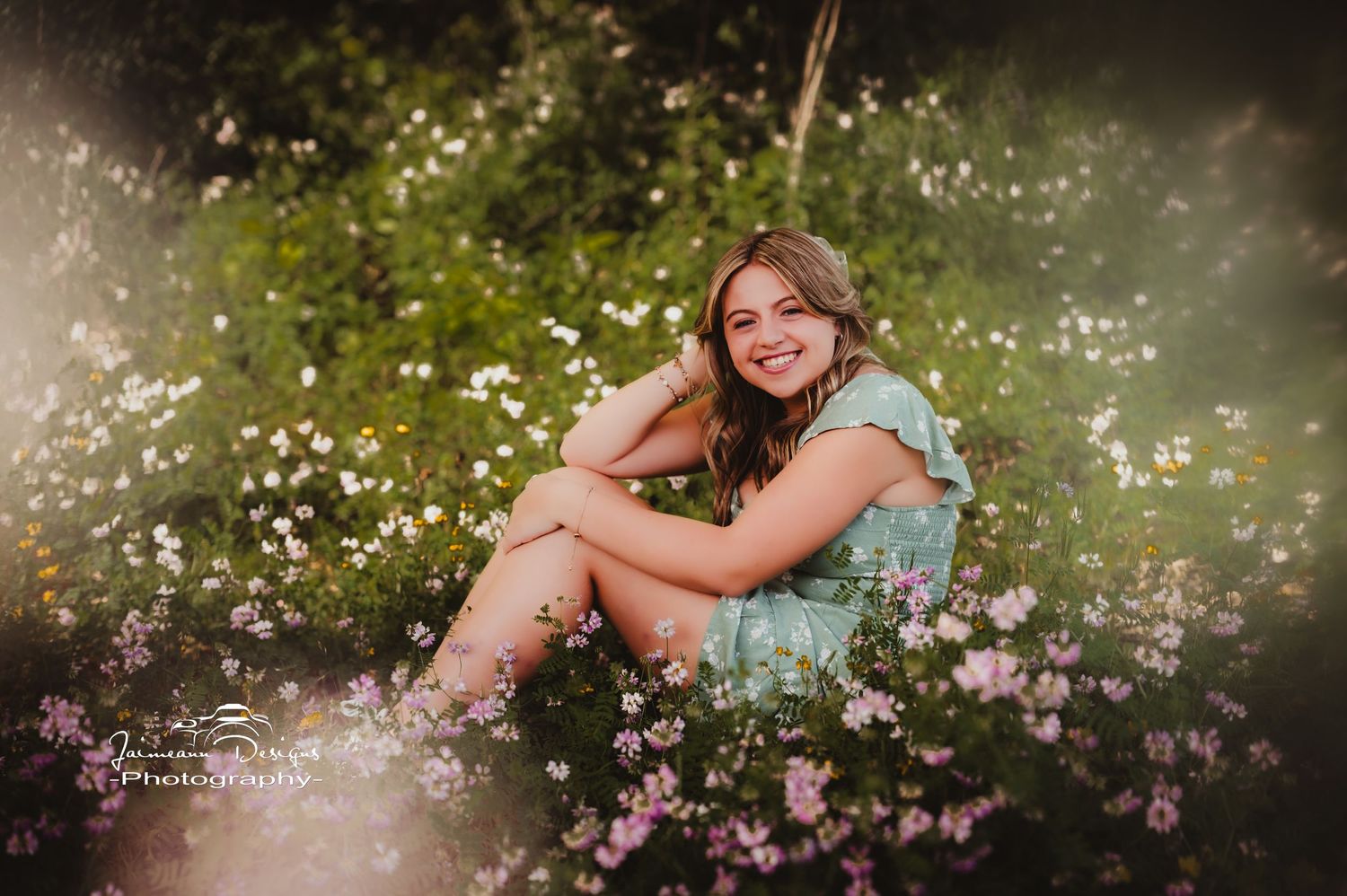 Portrait surrounded by pink wildflowers in a dreamy outdoor garden setting.
