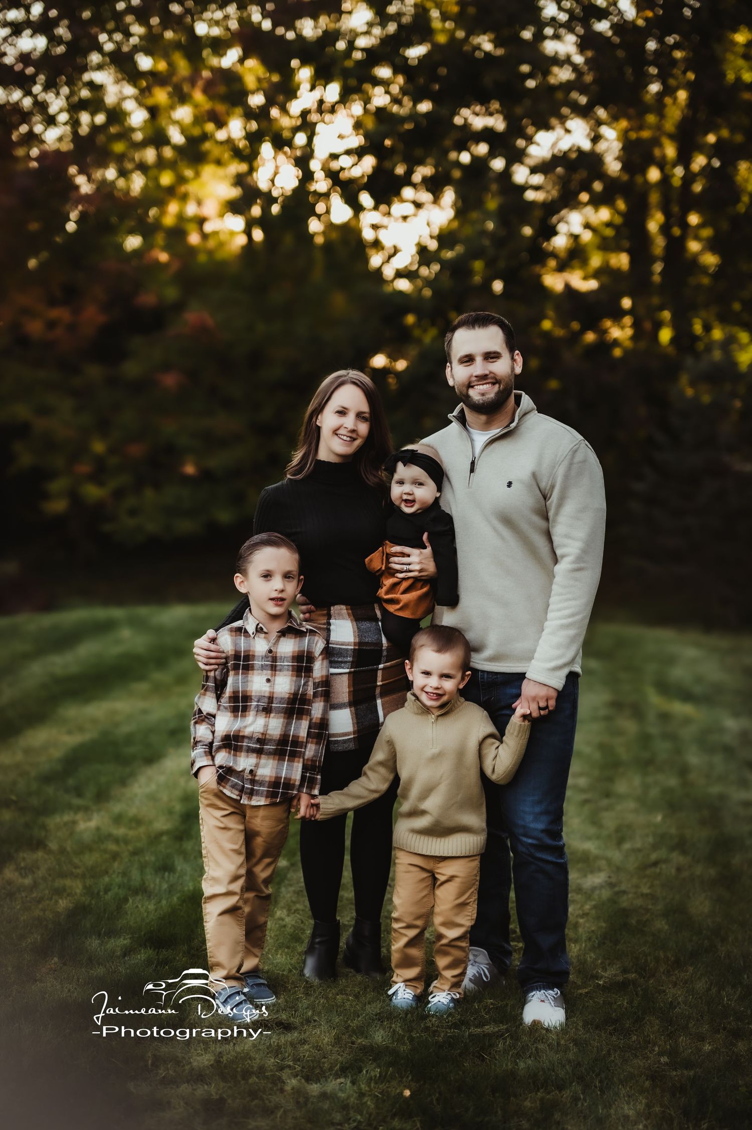 A family of five poses together at sunset in coordinated casual outfits.