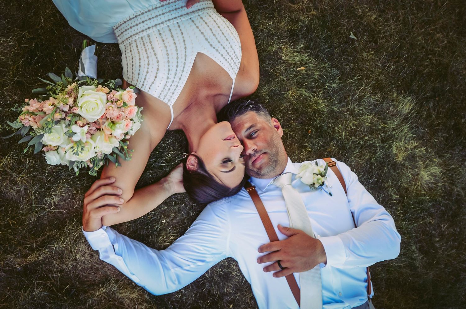 A romantic wedding couple embraces in a garden setting while sharing a tender moment together.