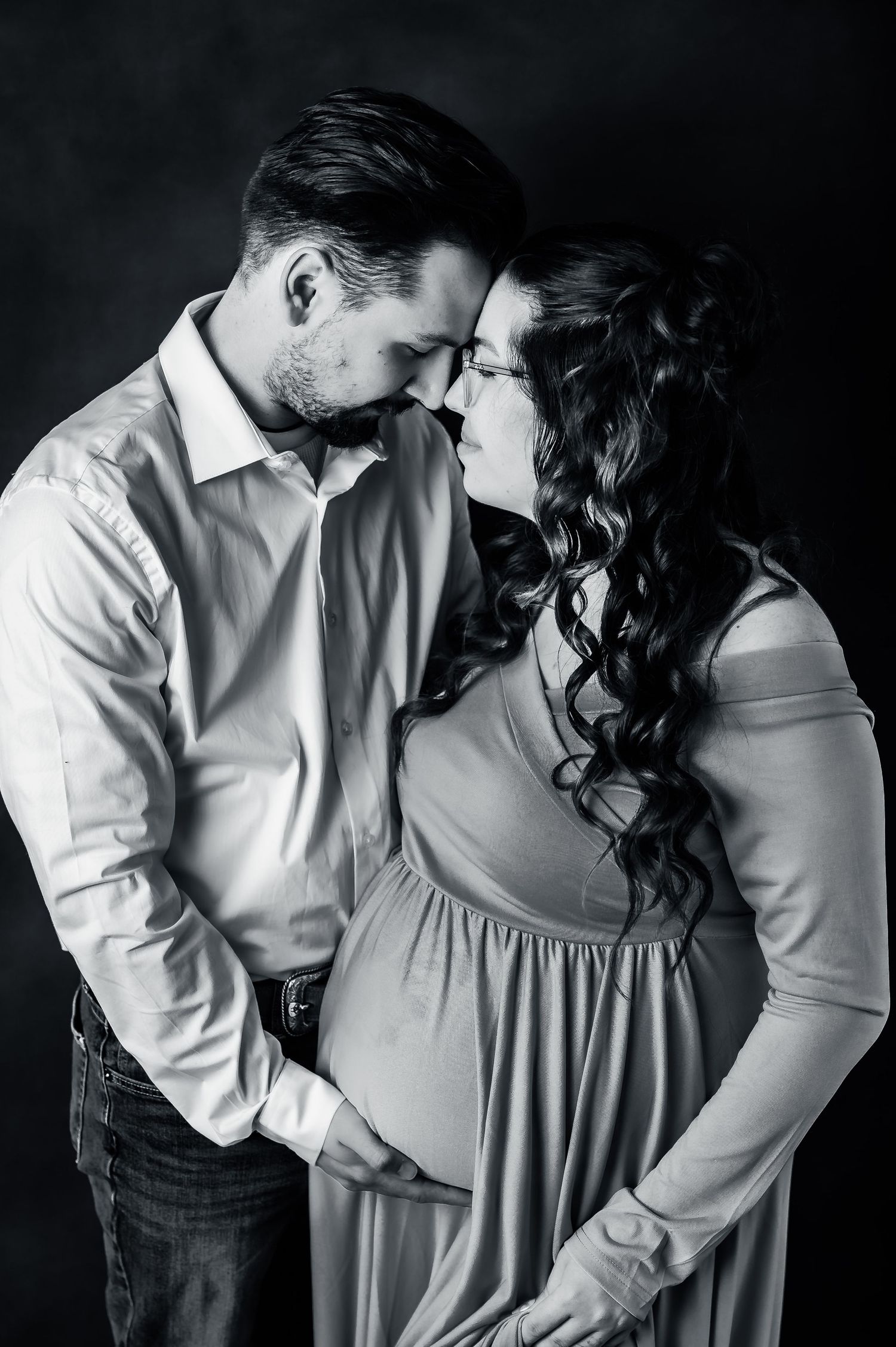 Intimate black and white maternity portrait of an expecting couple sharing a tender moment.