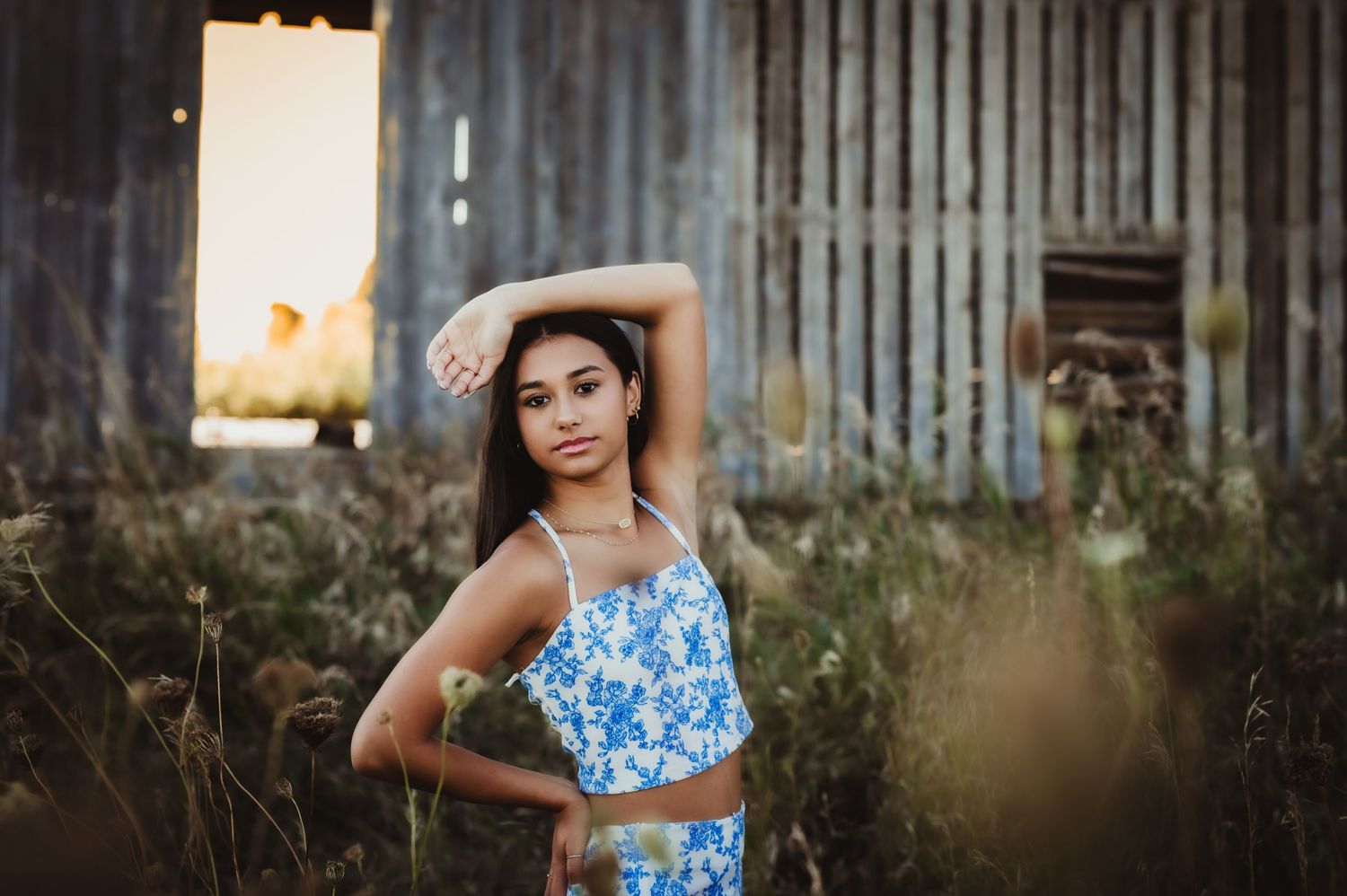 Portrait against rustic barn with person in blue floral outfit.