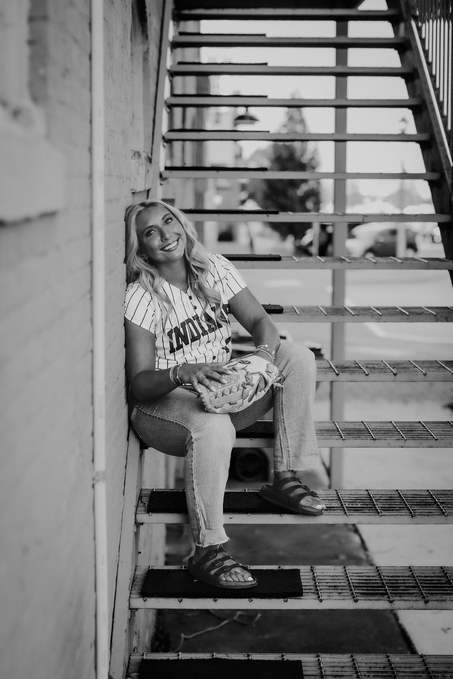 Black and white senior softball portrait on a metal staircase in Port Washington