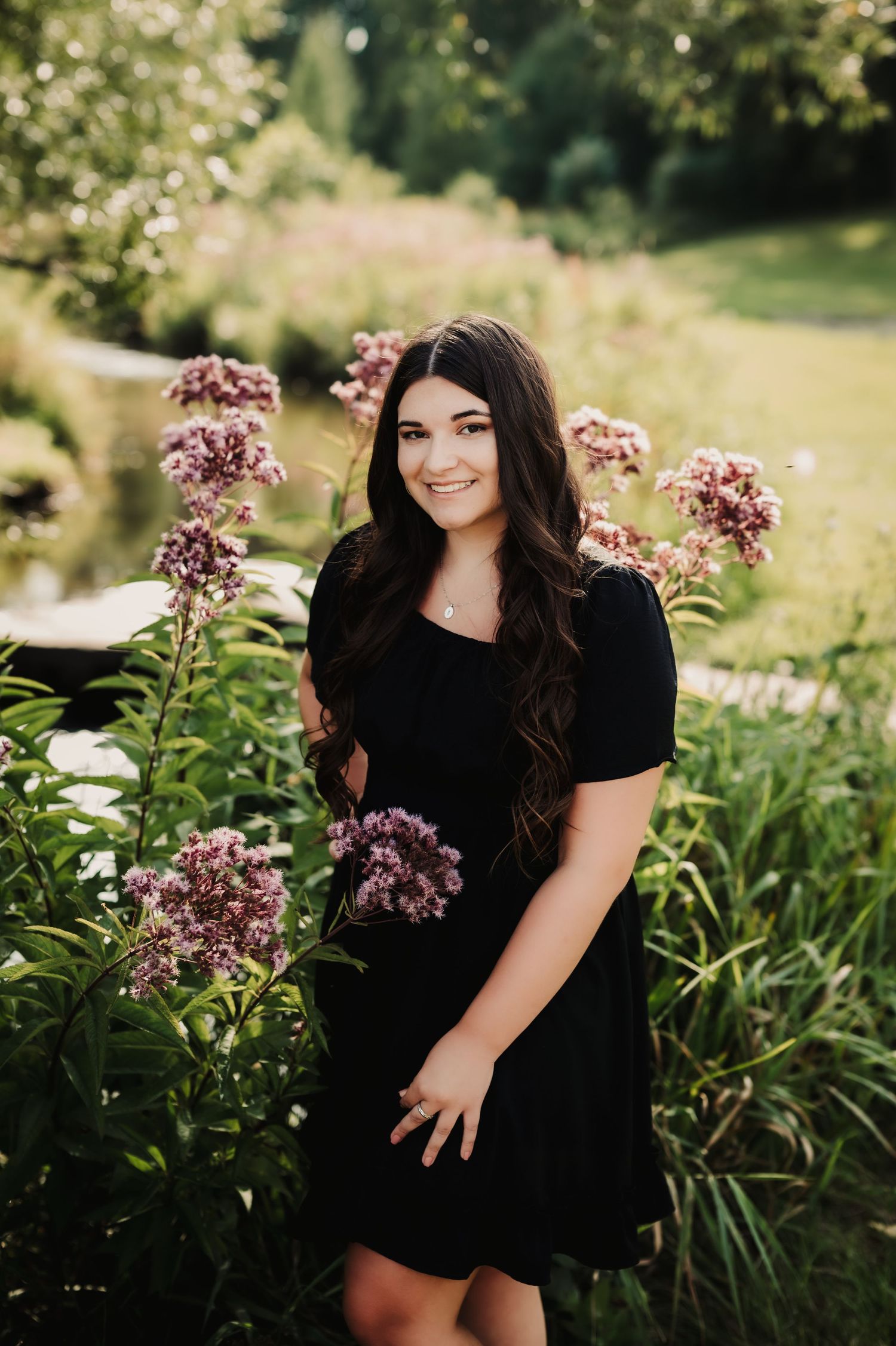 A black dress stands out against pink flowers and greenery in a garden setting.