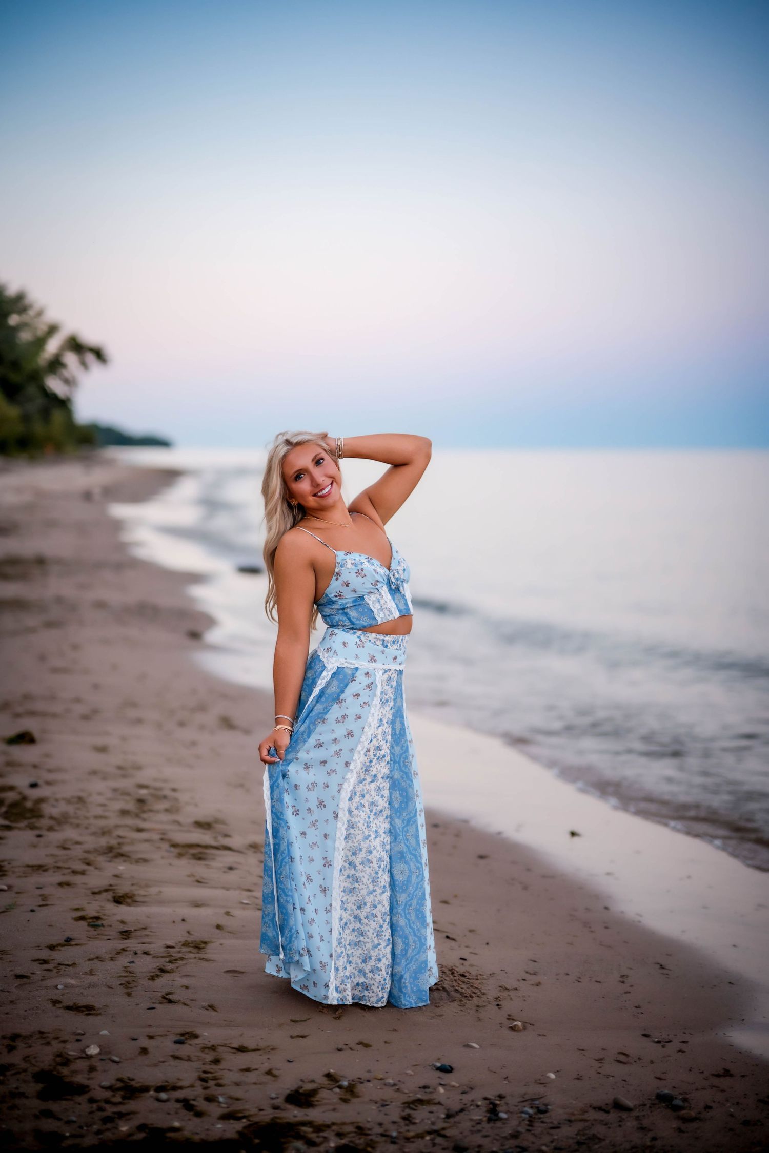Senior girl smiling with her hand in her hair on a Port Washington beach