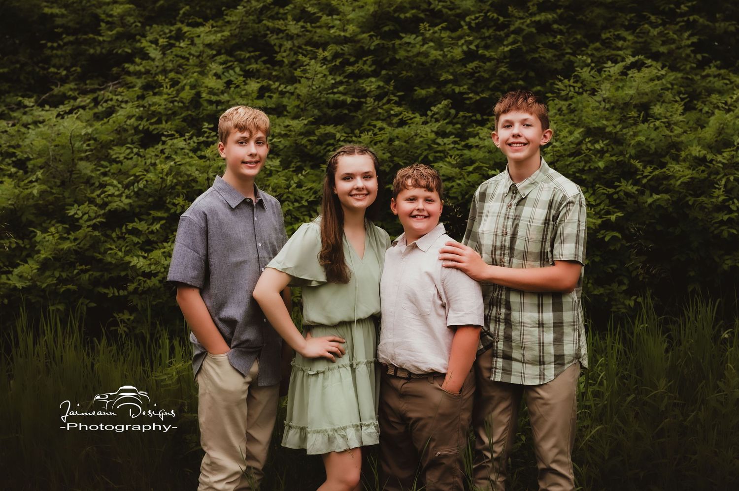 Group of siblings pose together for outdoor family portrait in coordinated casual outfits.