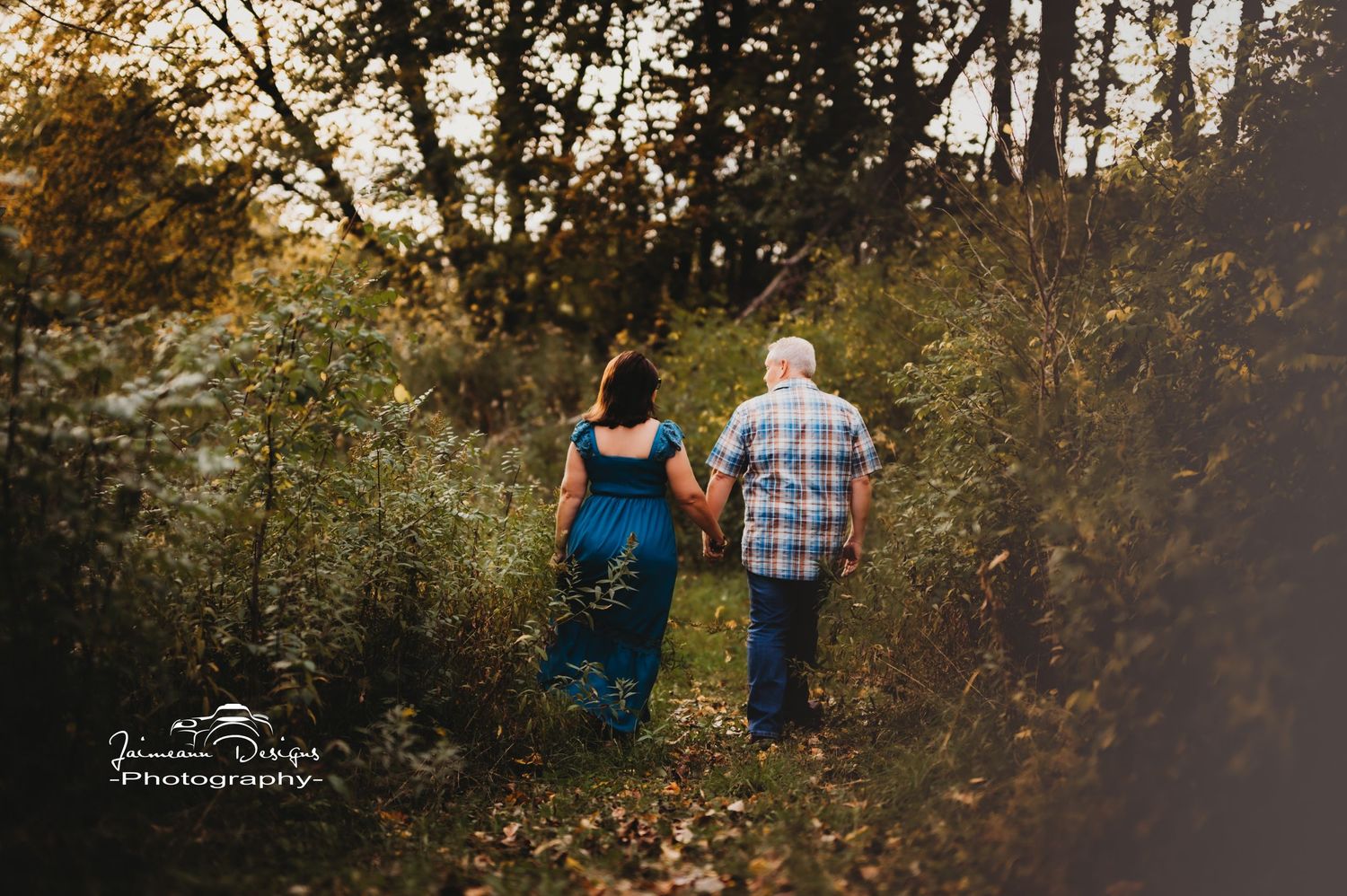 Romantic couple walking together through wooded nature trail during sunset.