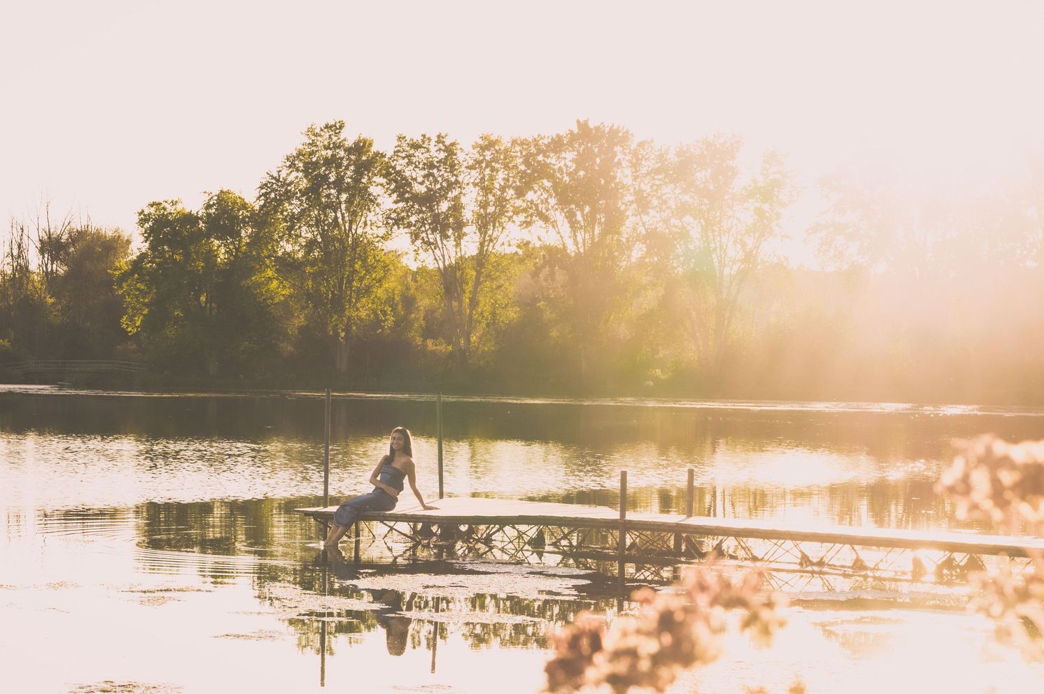 Misty lake scene at sunset with dock silhouette and golden light.