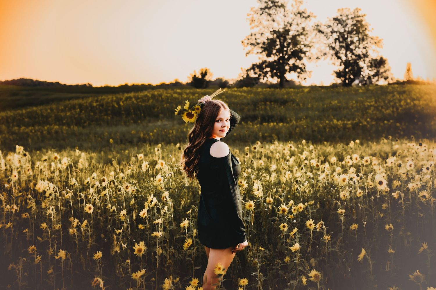 A romantic sunset photoshoot in a field of wildflowers with golden light filtering through the trees.