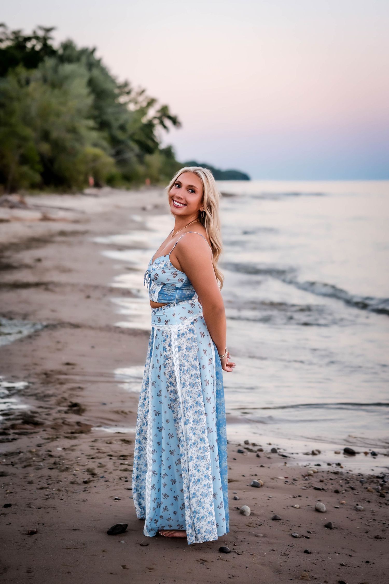 Senior girl posing on the beach at sunset with Lake Michigan behind her