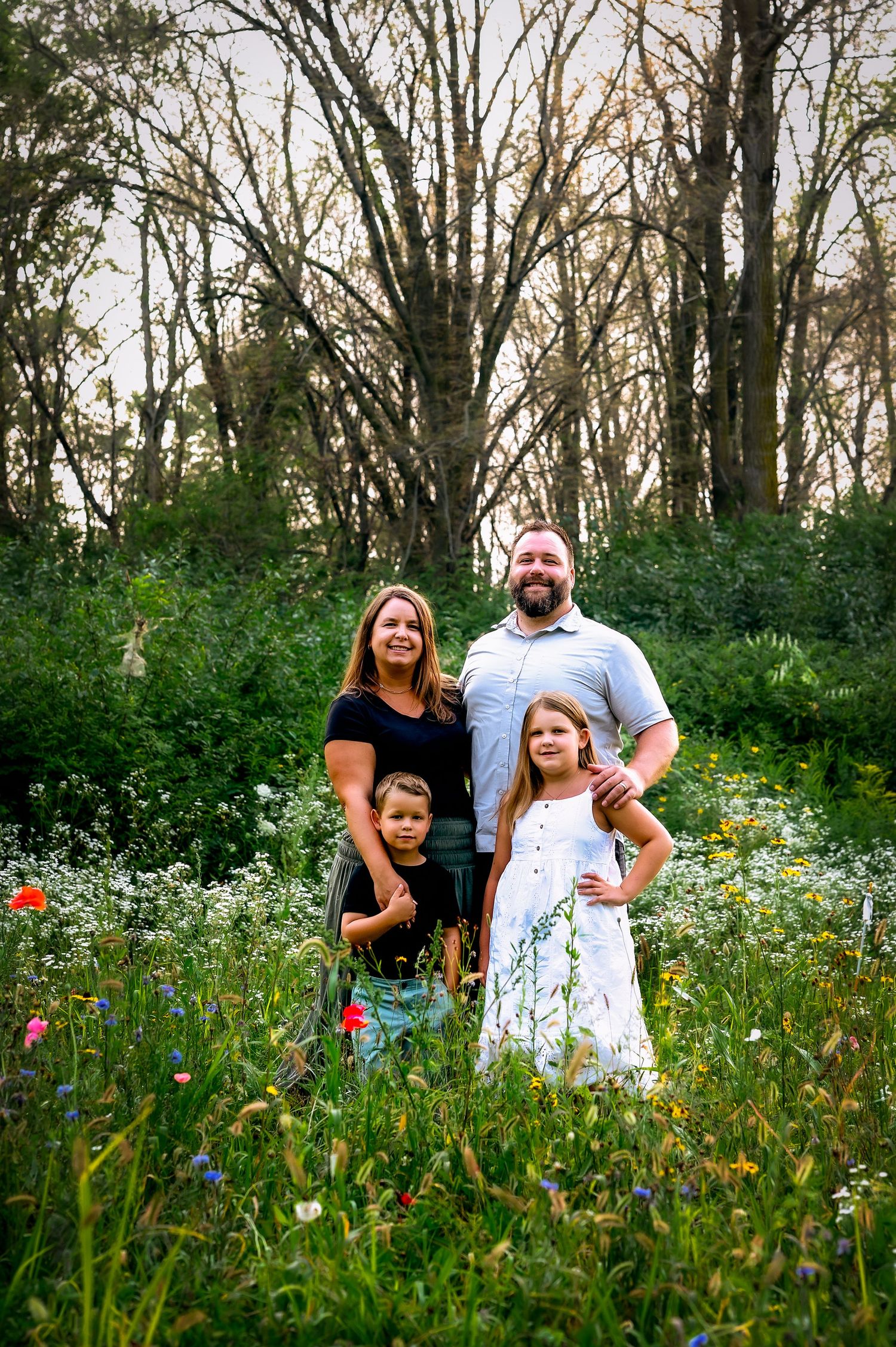 A group stands together in a wildflower meadow with tall trees in the background during golden hour in private wildflower field, Kewaskum, W