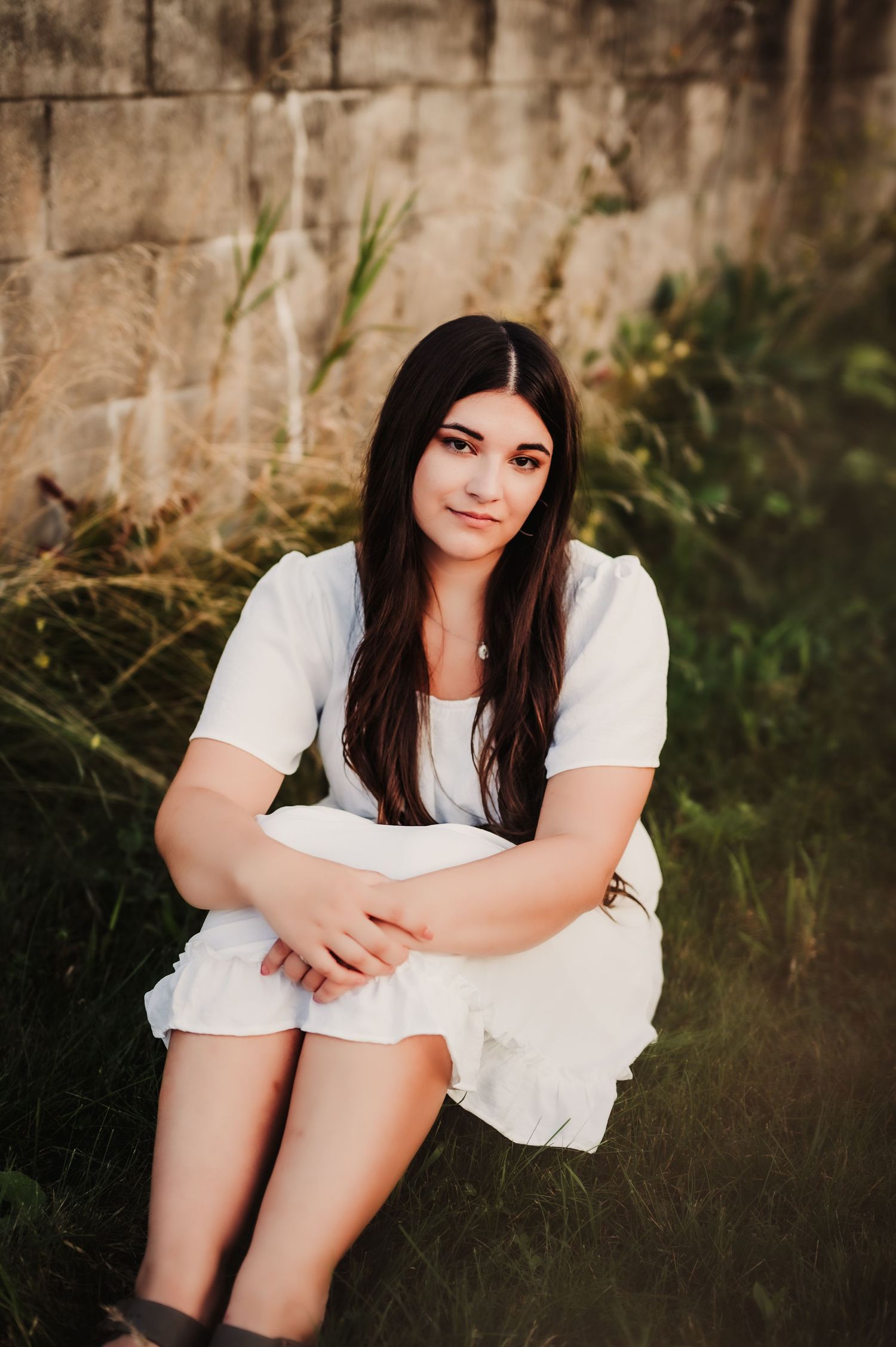 Casual portrait against textured stone wall with natural vegetation.