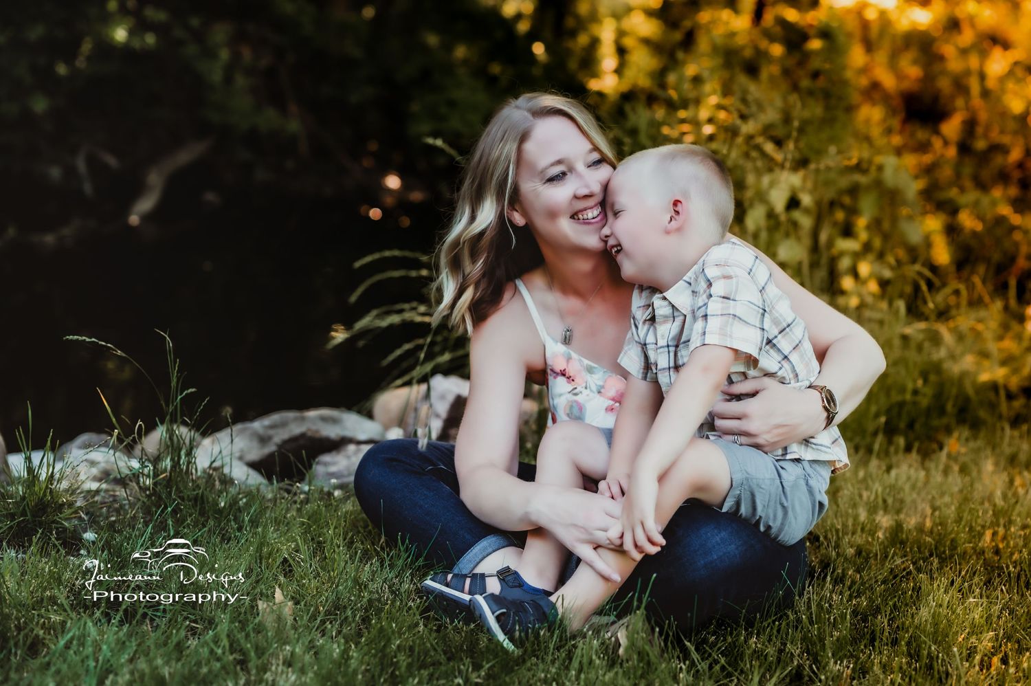 Candid moment of affection captured between parent and child on grassy ground during sunset.
