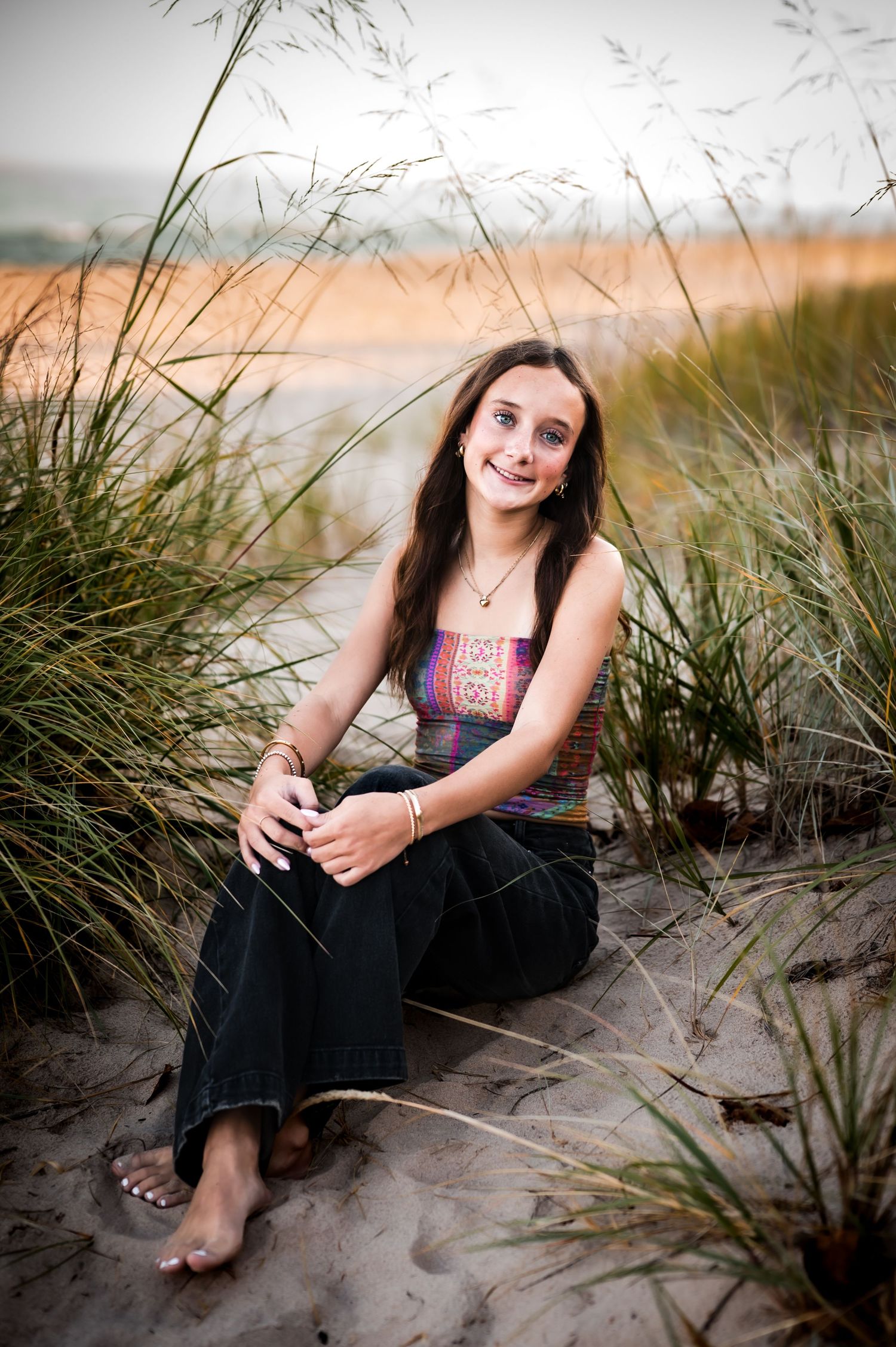 A series of beach portraits showing someone sitting among coastal dunes and sea grass at sunset in Port Washington, WI