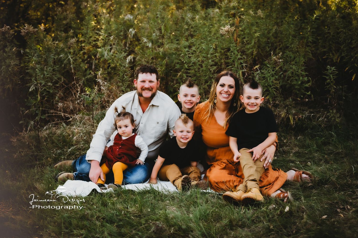 A family group photo outdoors with everyone wearing coordinated fall colors.