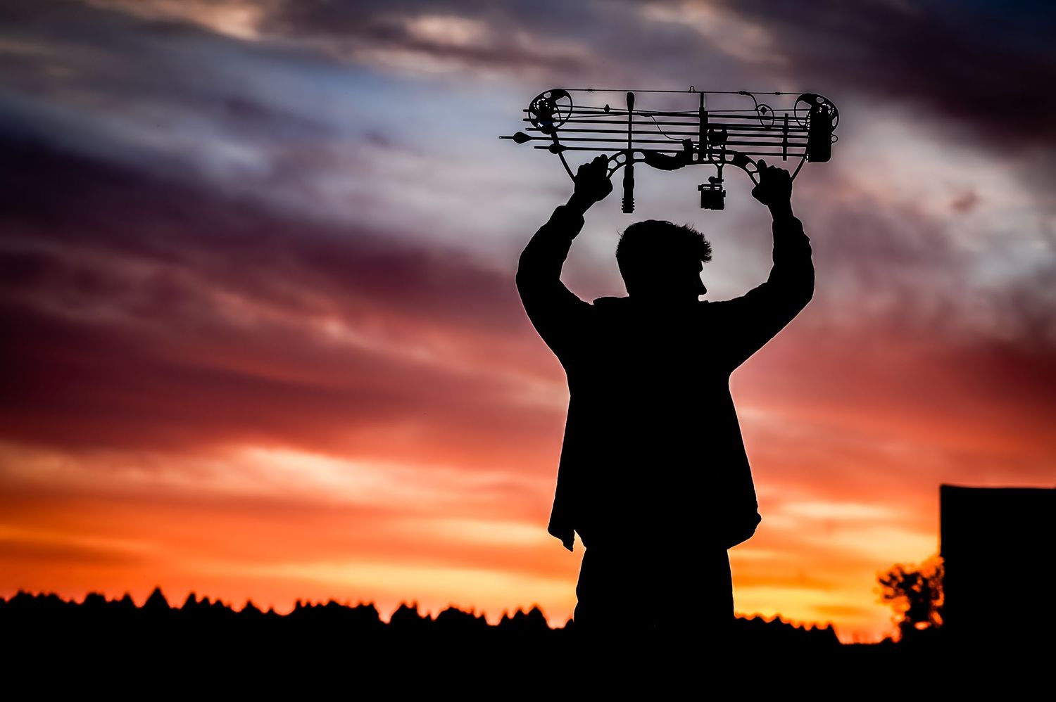 Silhouette of a figure holding music notes against a dramatic sunset sky.