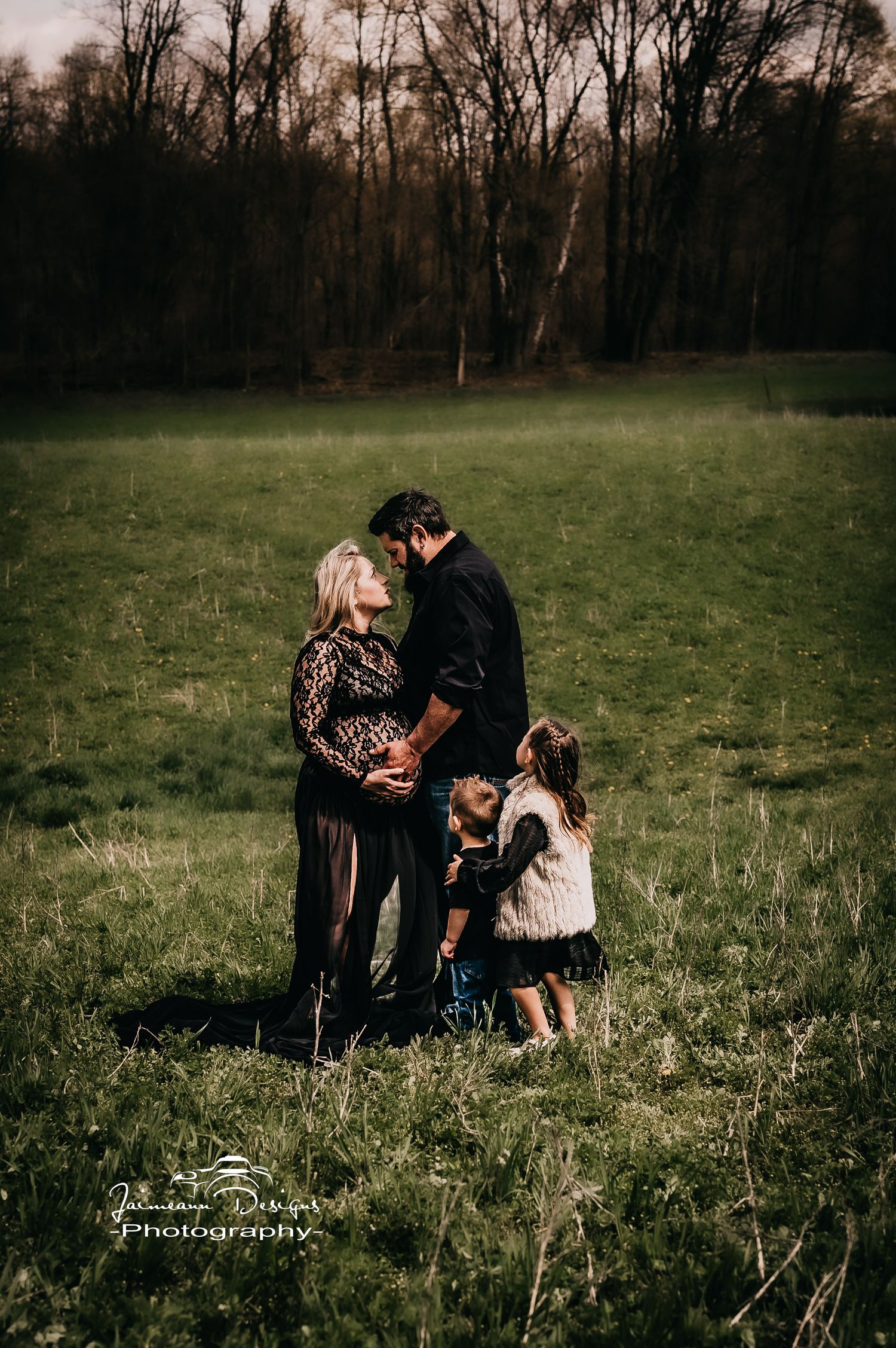 Intimate family portrait outdoors in a grassy field at sunset.