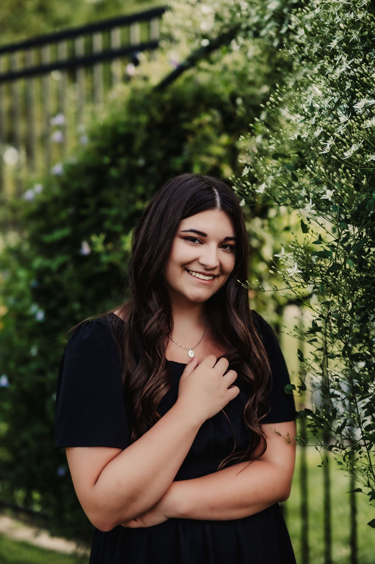 Portrait against lush greenery and garden fence in natural outdoor setting.