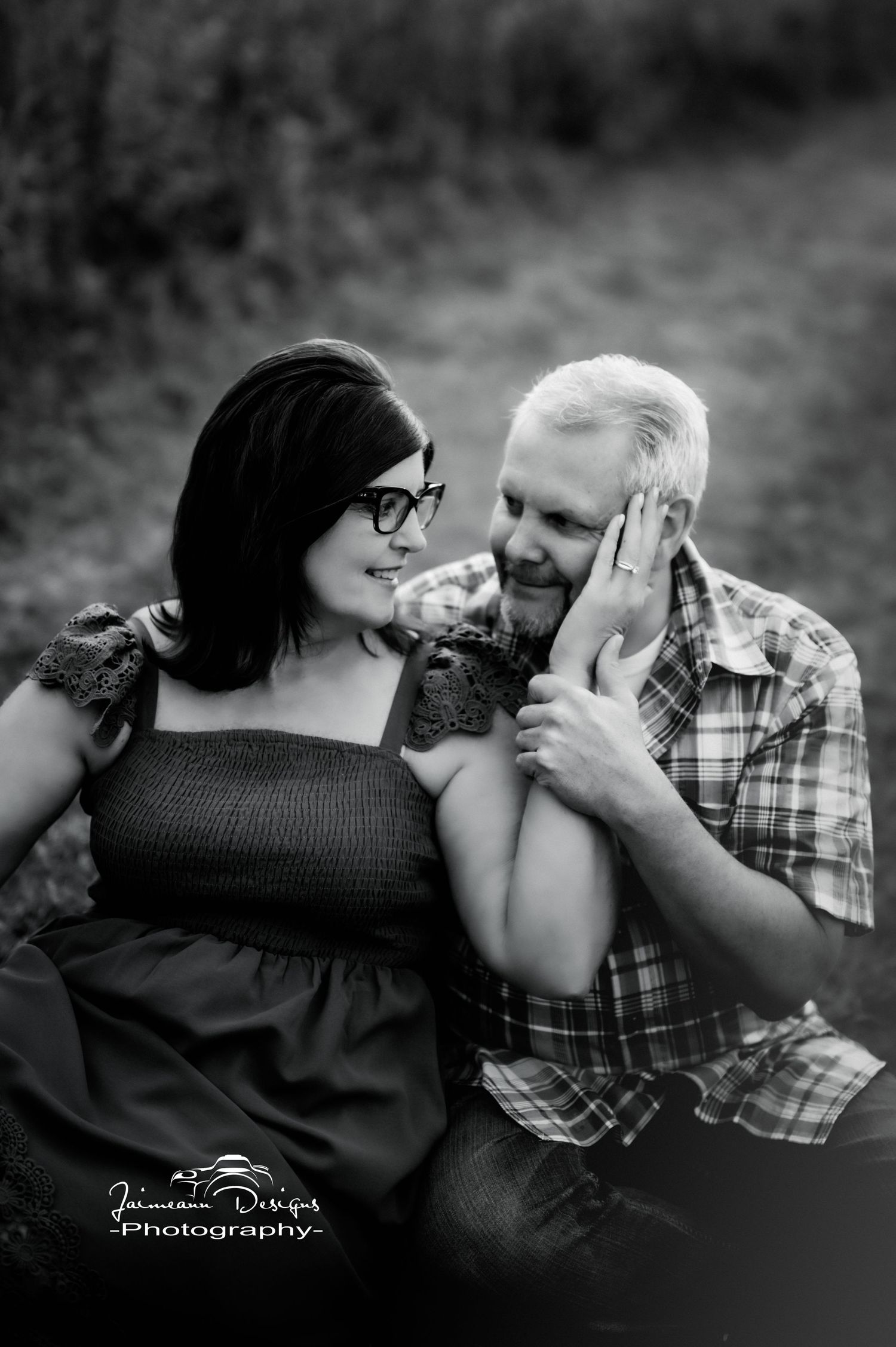 Intimate black and white portrait of couple sharing tender moment outdoors.