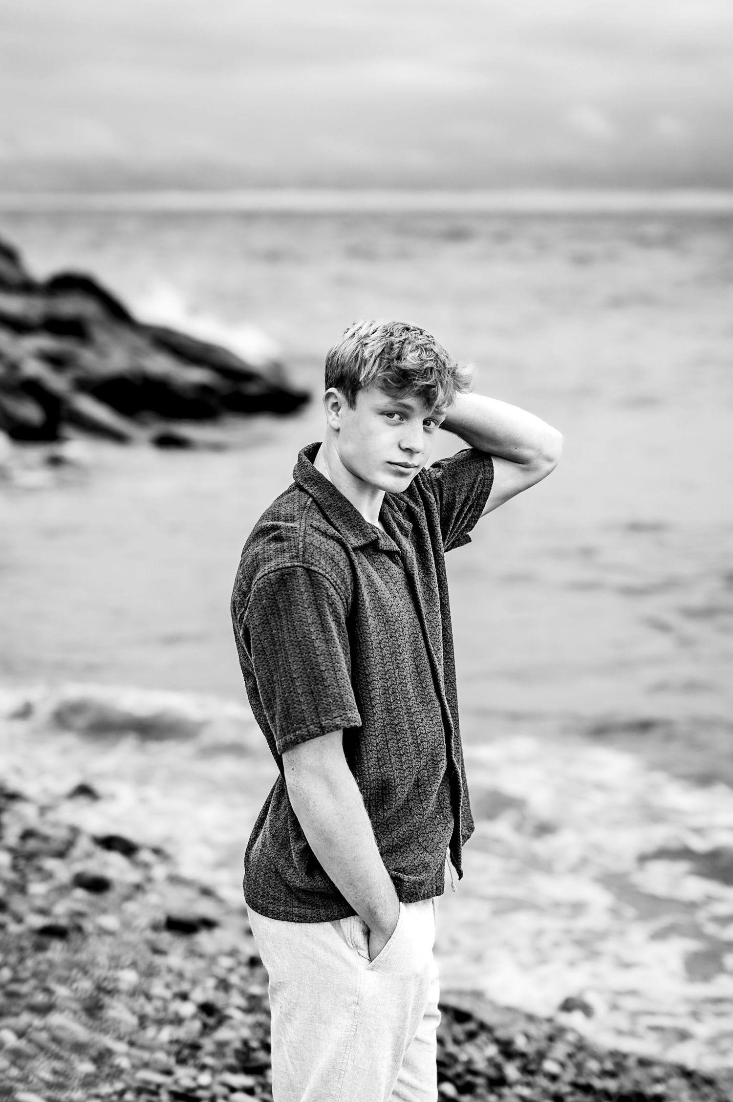 Black and white photo of a young boy standing on a beach looking out at the ocean waves in Port Washington, WI Beach front.