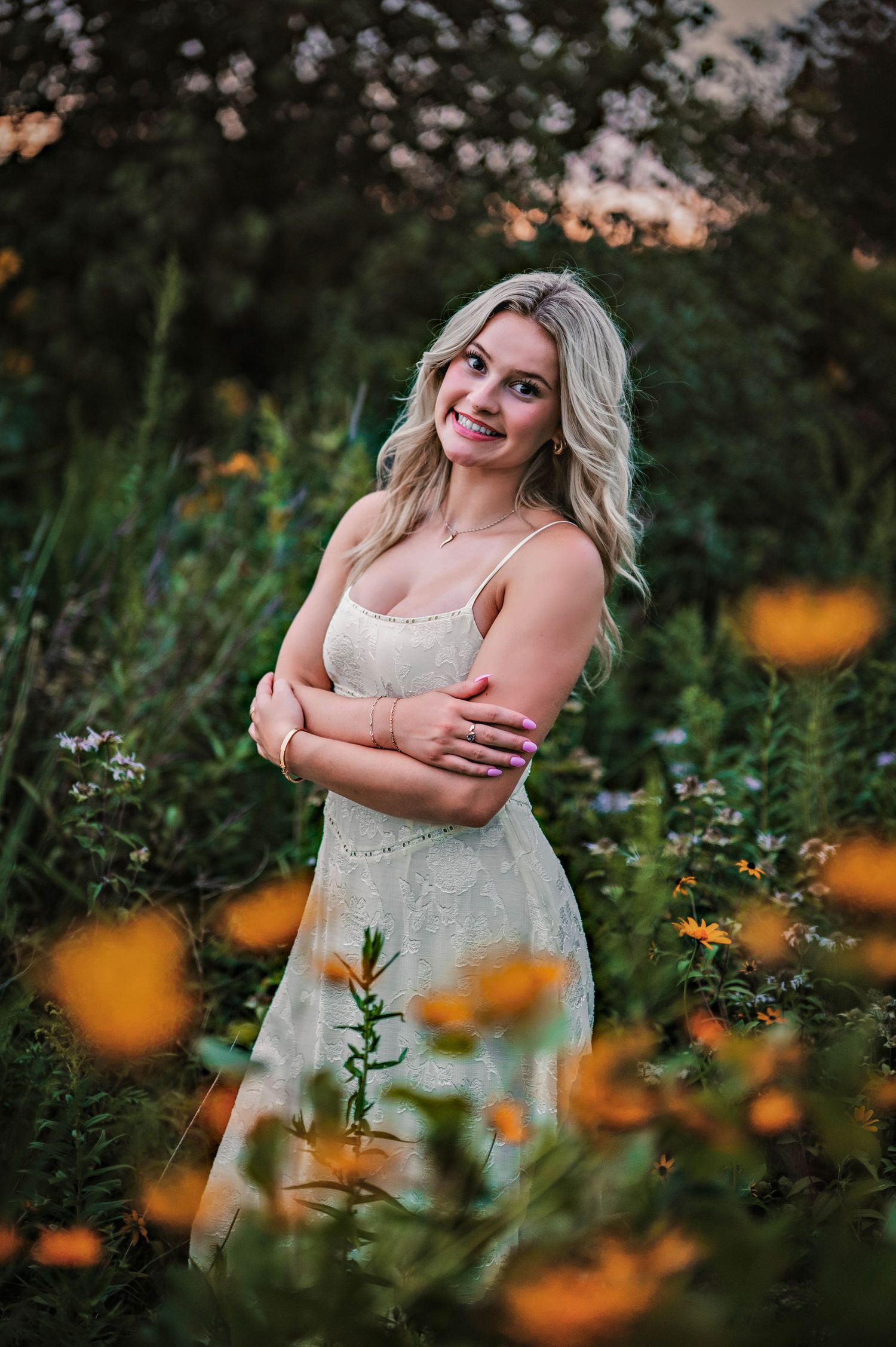 A woman in a white dress stands among orange wildflowers at sunset in a dreamy outdoor portrait session. Near Oconomowoc, WI