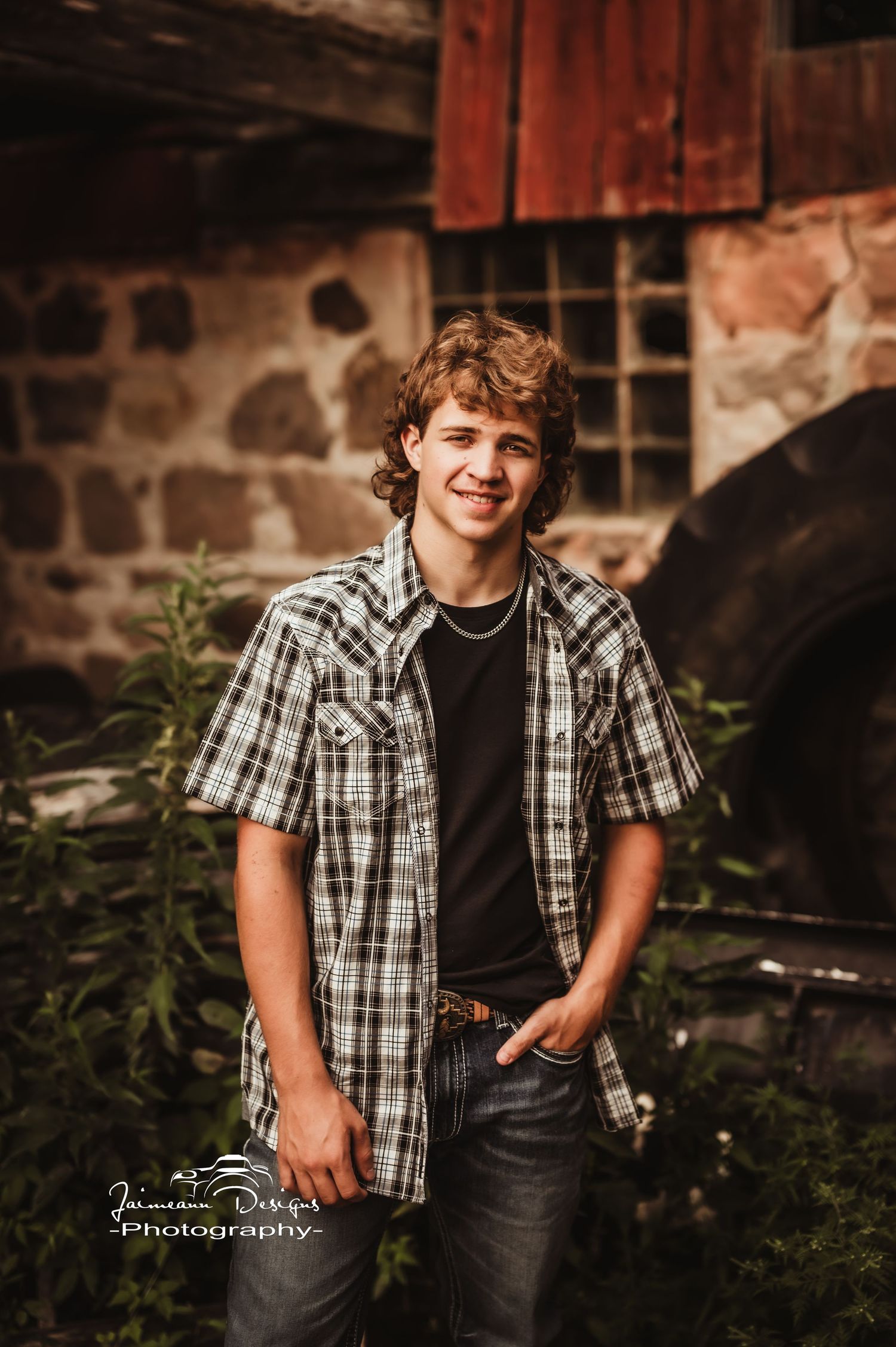 A casual outdoor portrait against a rustic stone and wood building in warm lighting.