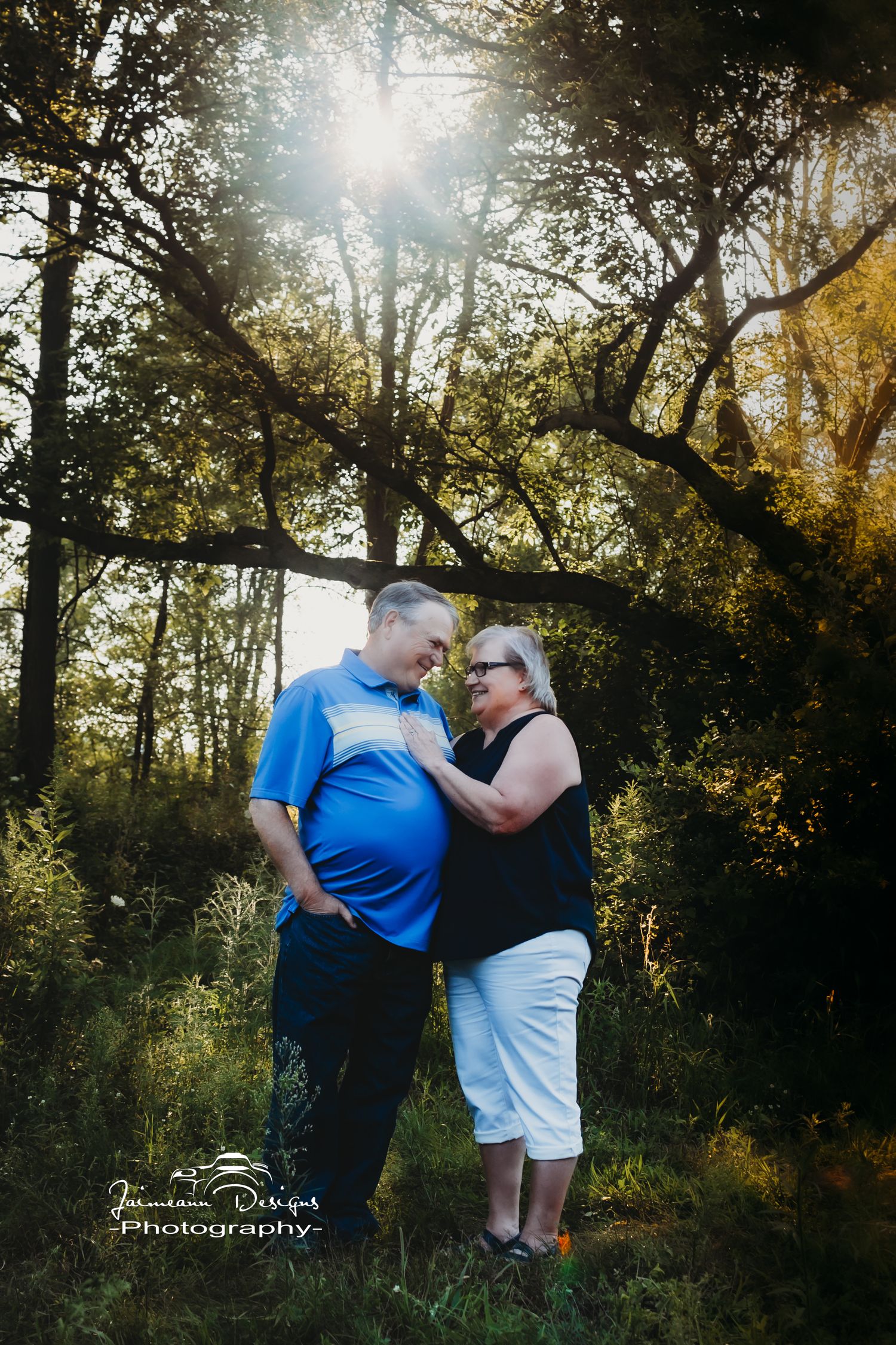 Intimate couple's portrait under sunlit trees in a romantic outdoor setting.